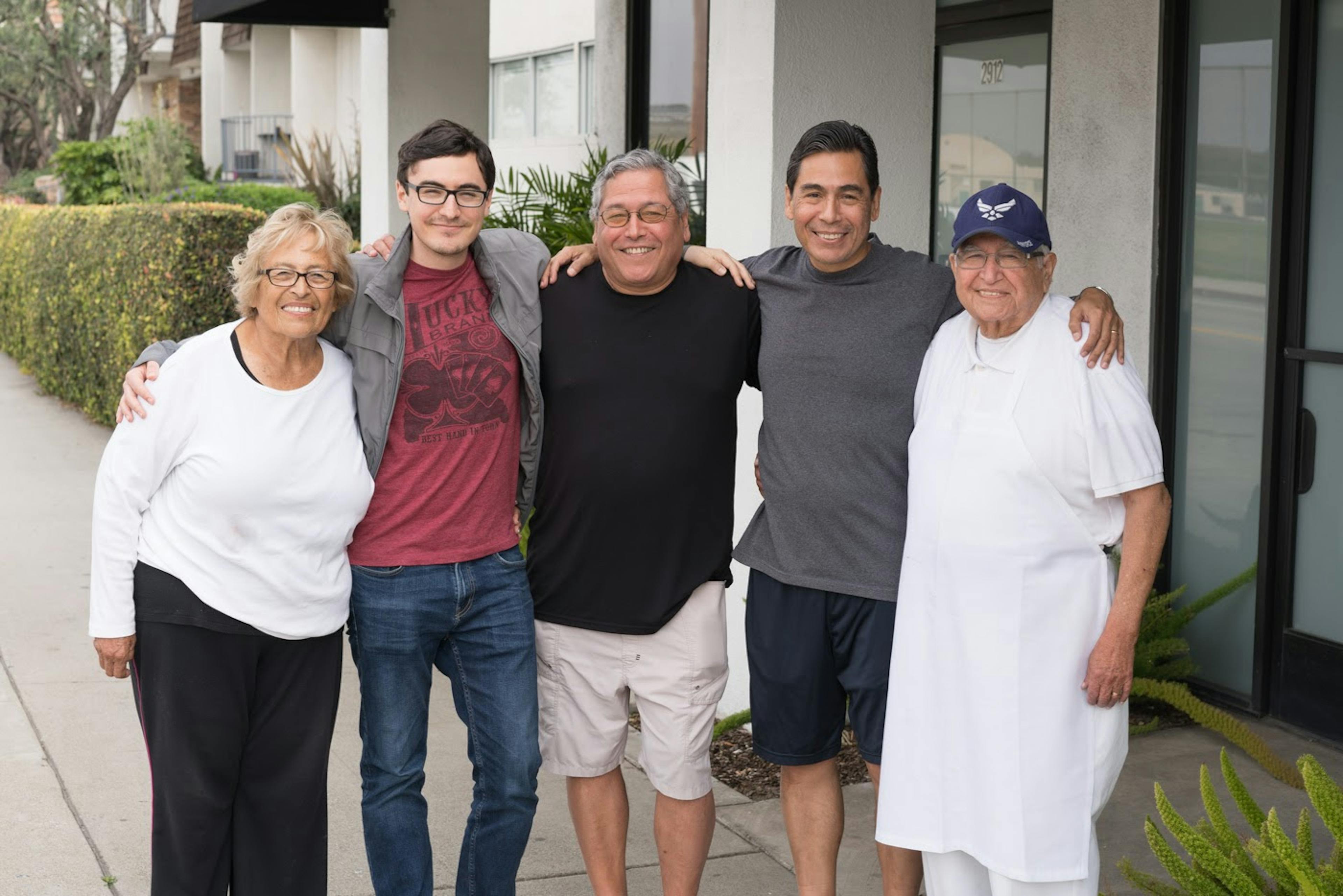 Image of three generations of the Primo family standing outside of one of their donut shops