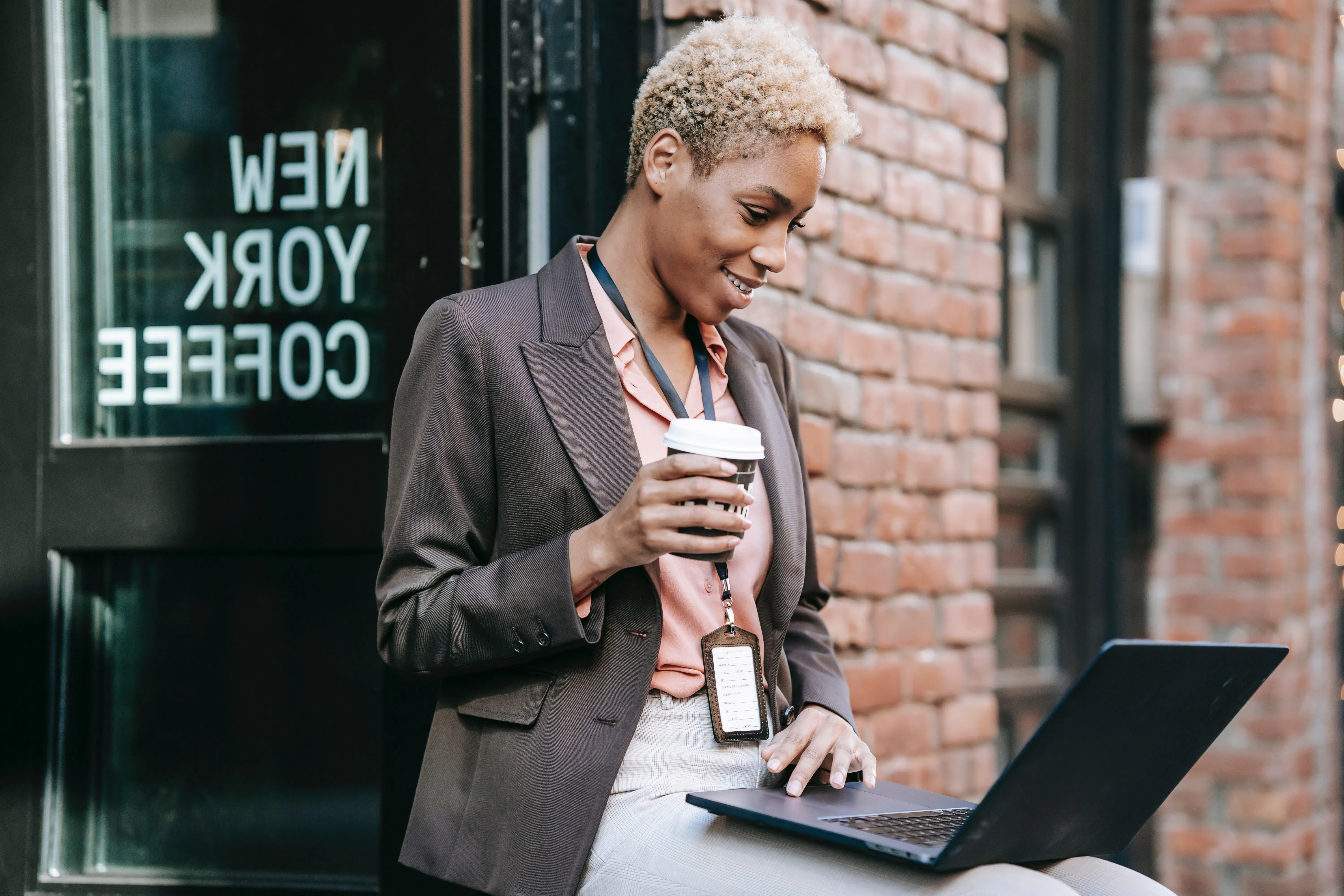 A woman working on her laptop outside of a coffee shop.