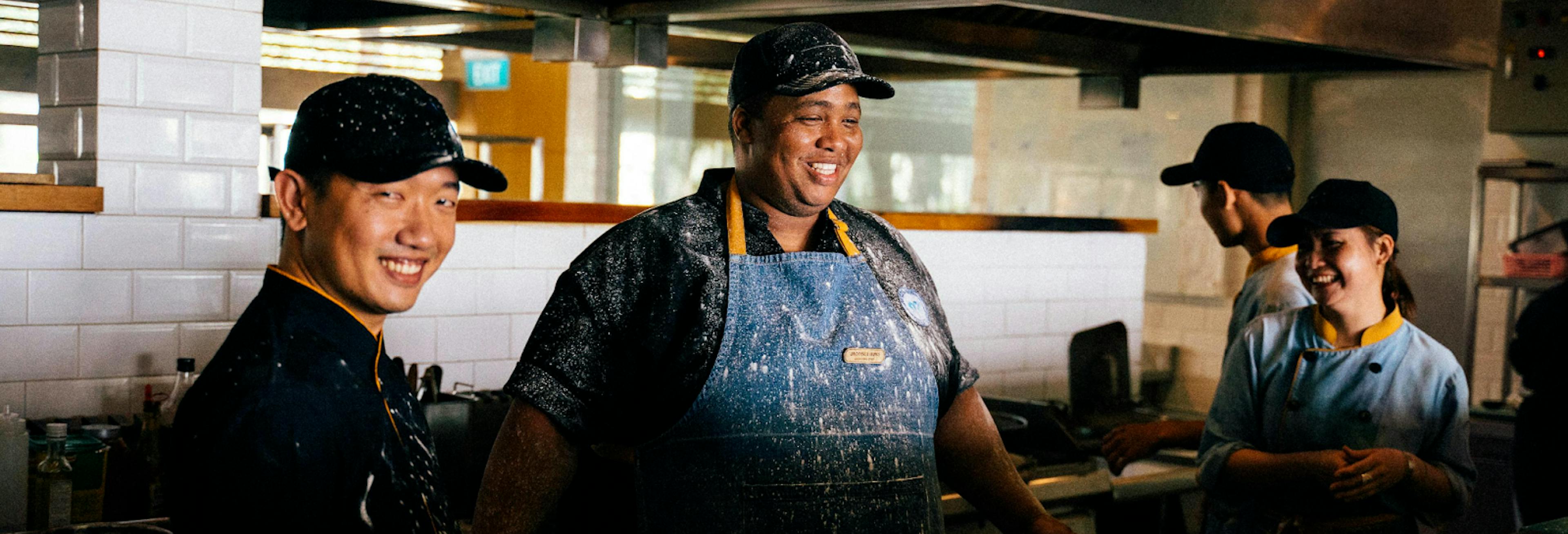 Some restaurant owners and staff working in a kitchen. 