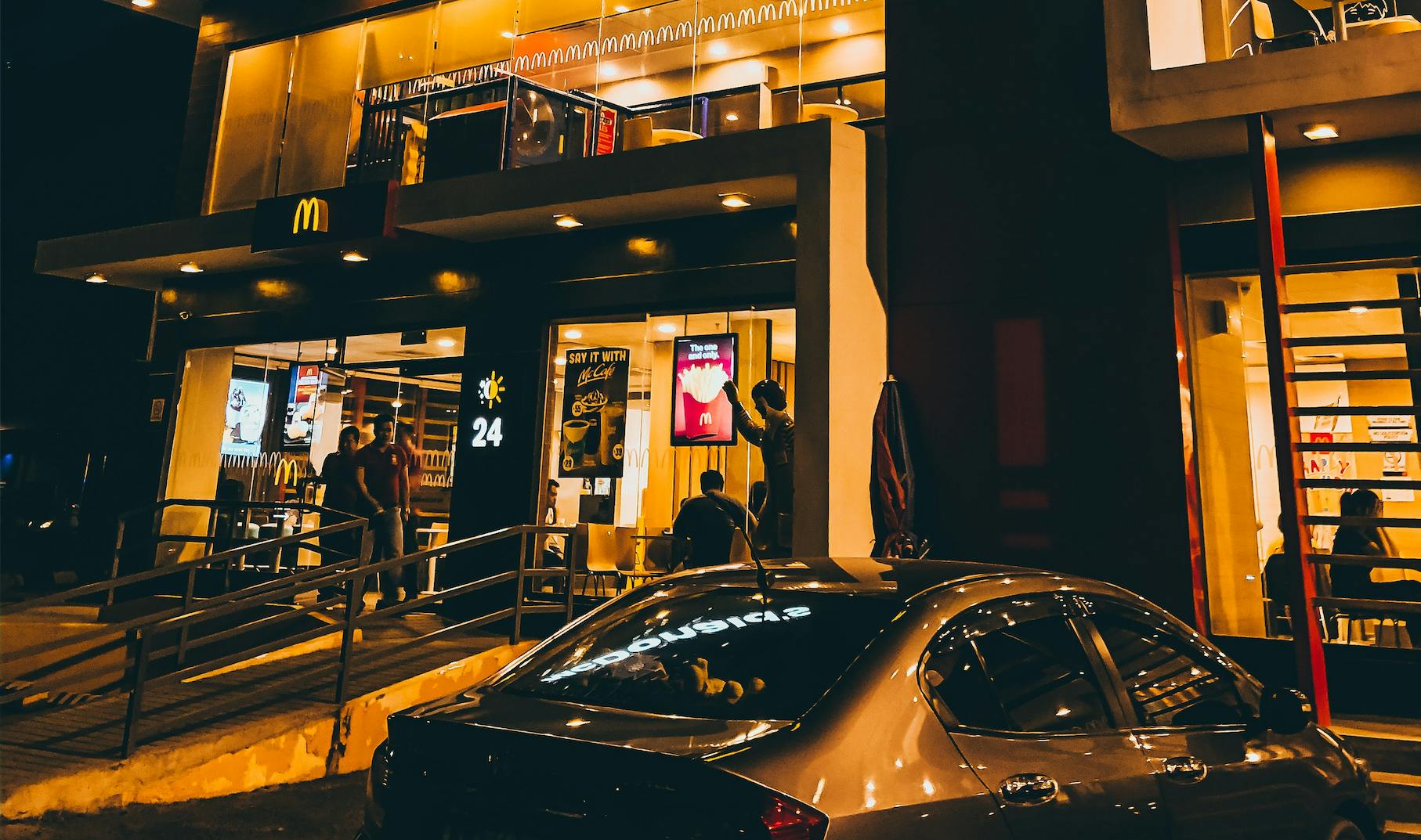 Outside of a McDonalds franchise at night.