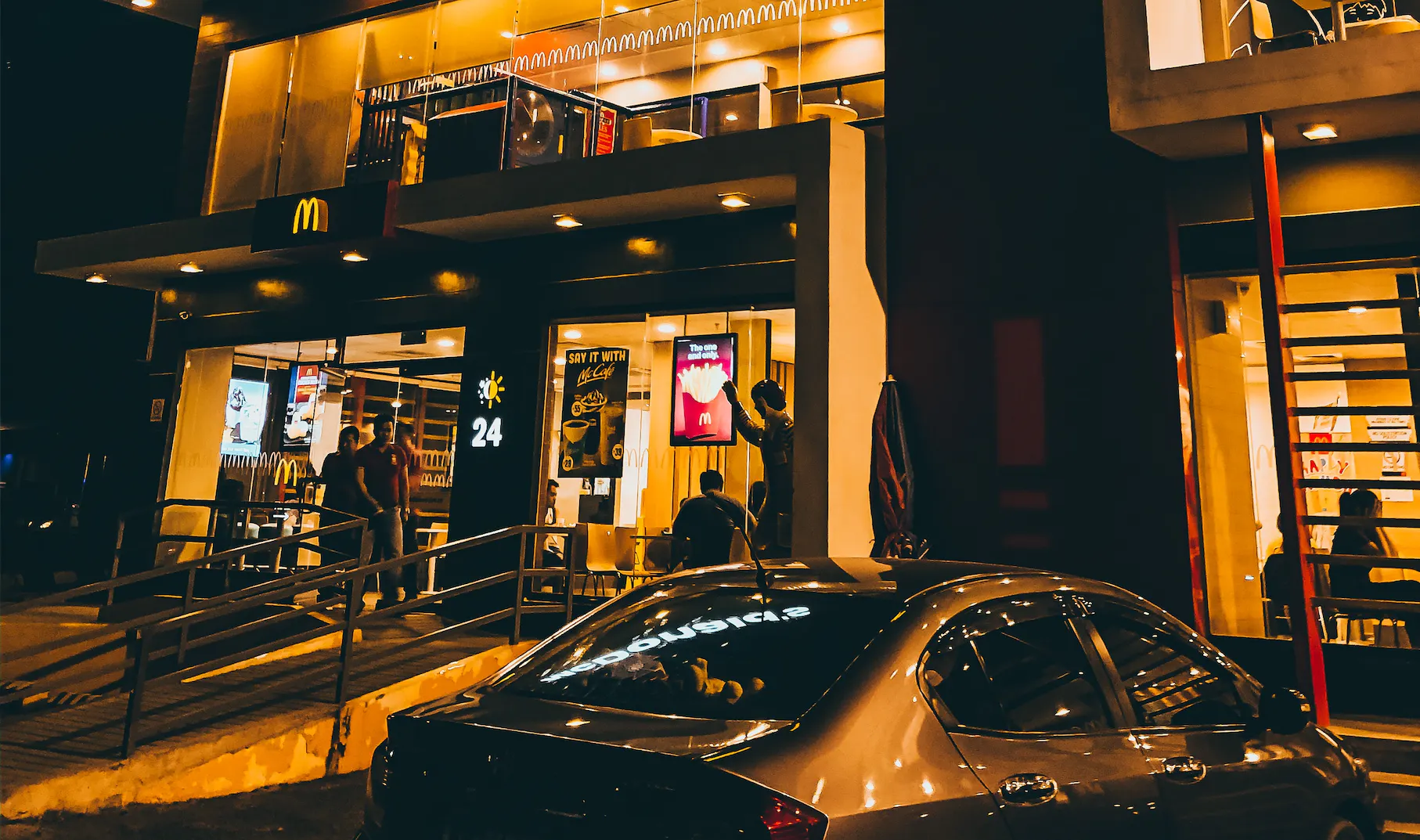 Outside of a McDonalds franchise at night.