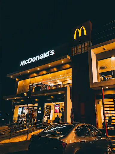 Outside of a McDonalds franchise at night. 
