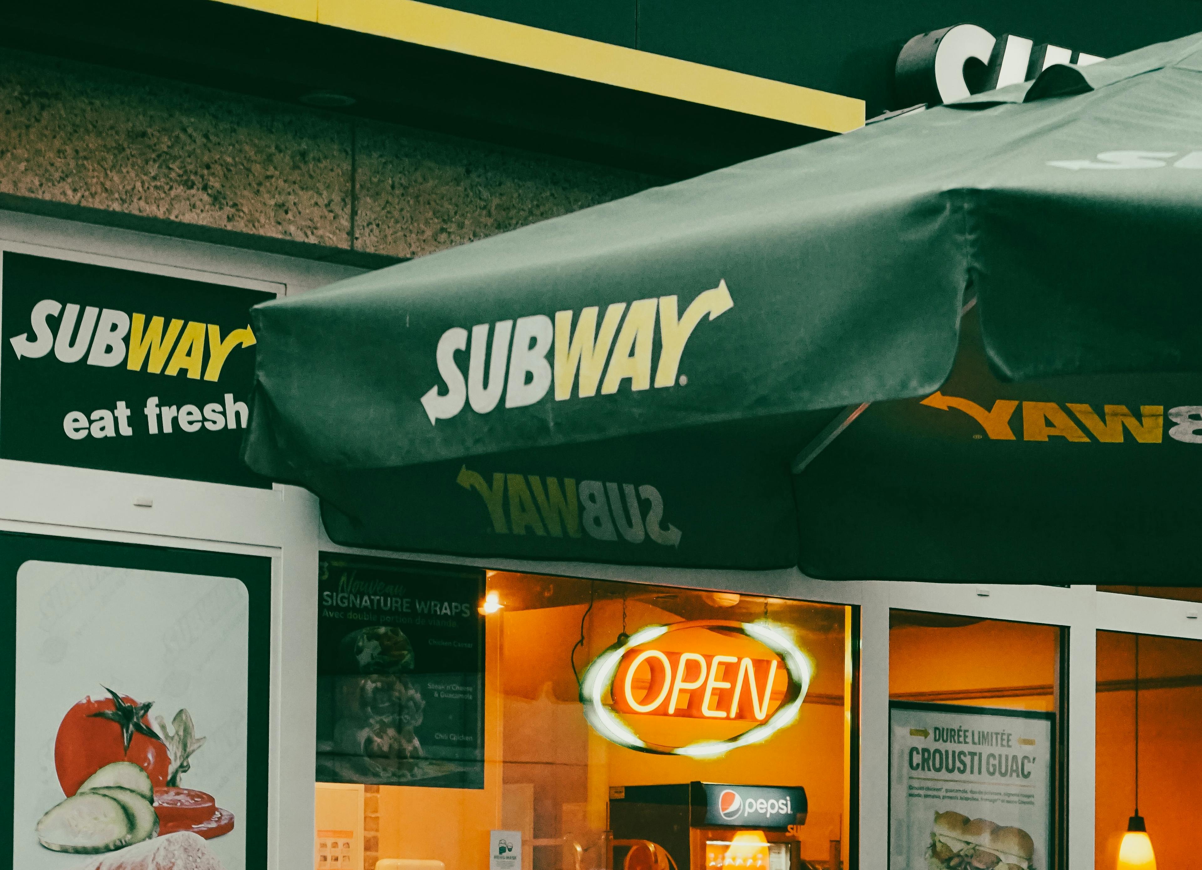 Outside a Subway franchise with a sign that says "open." 