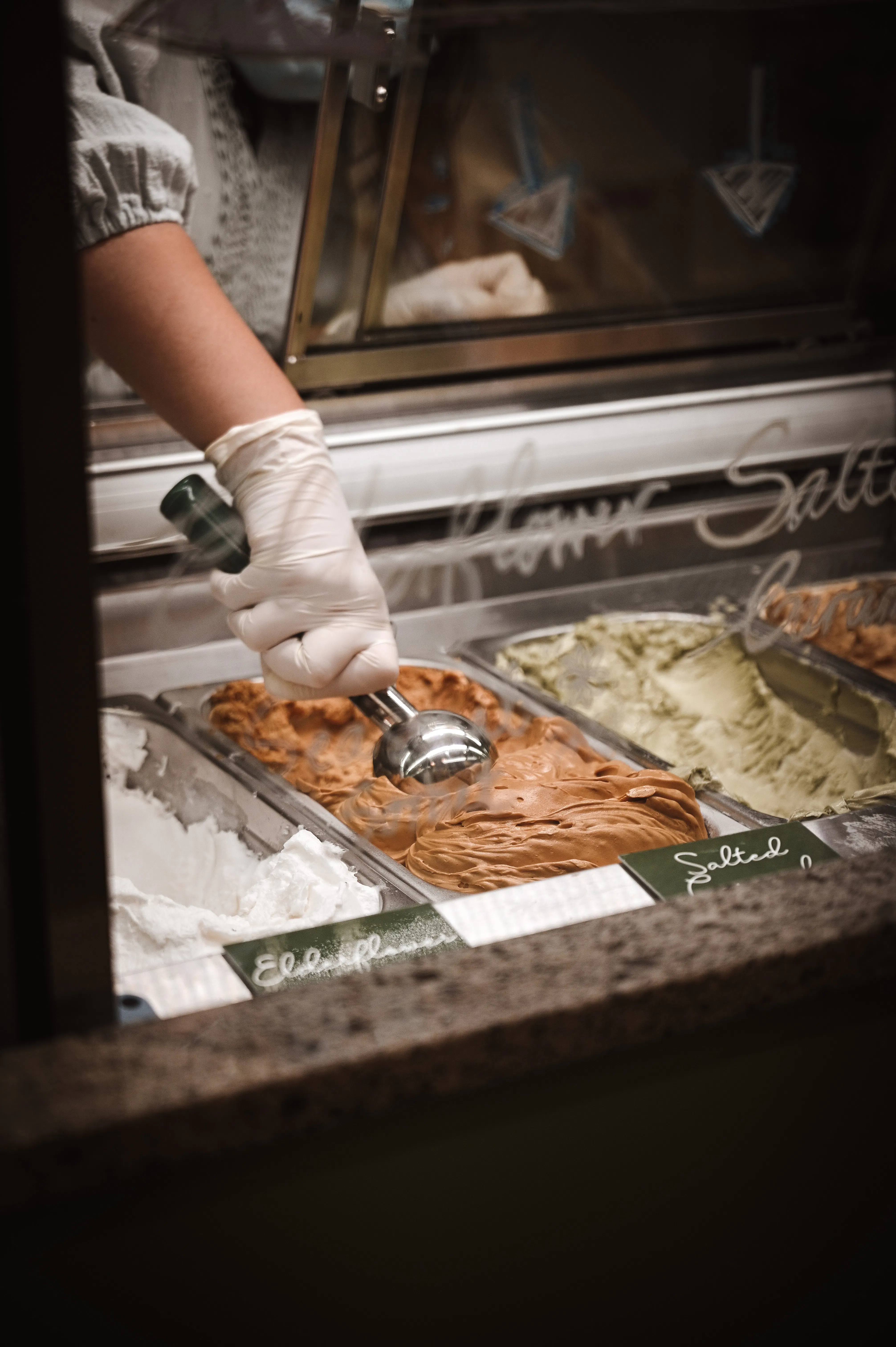 Ice cream being scooped in an ice cream parlor. 