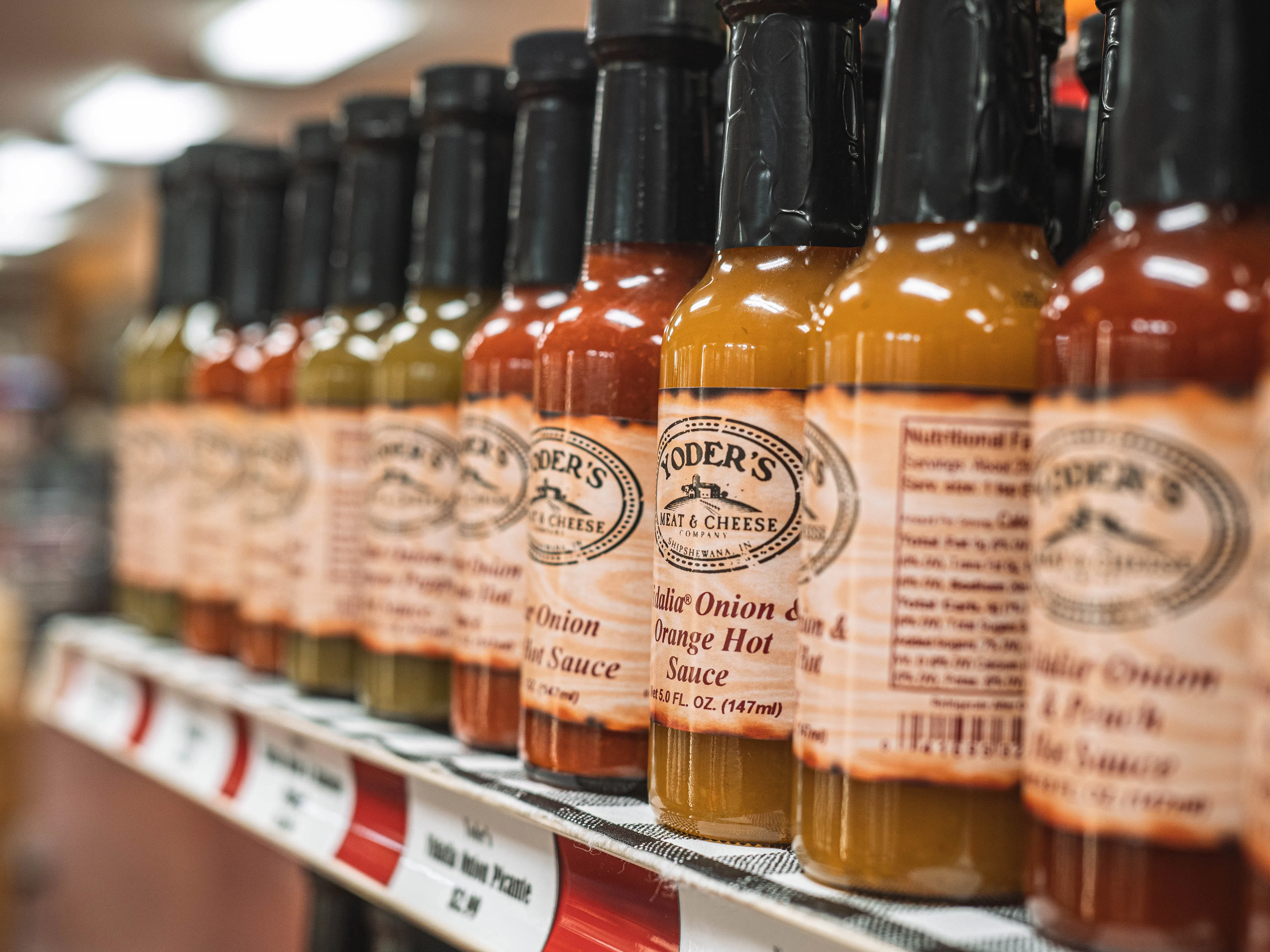 Some condiment bottles on a shelf. 