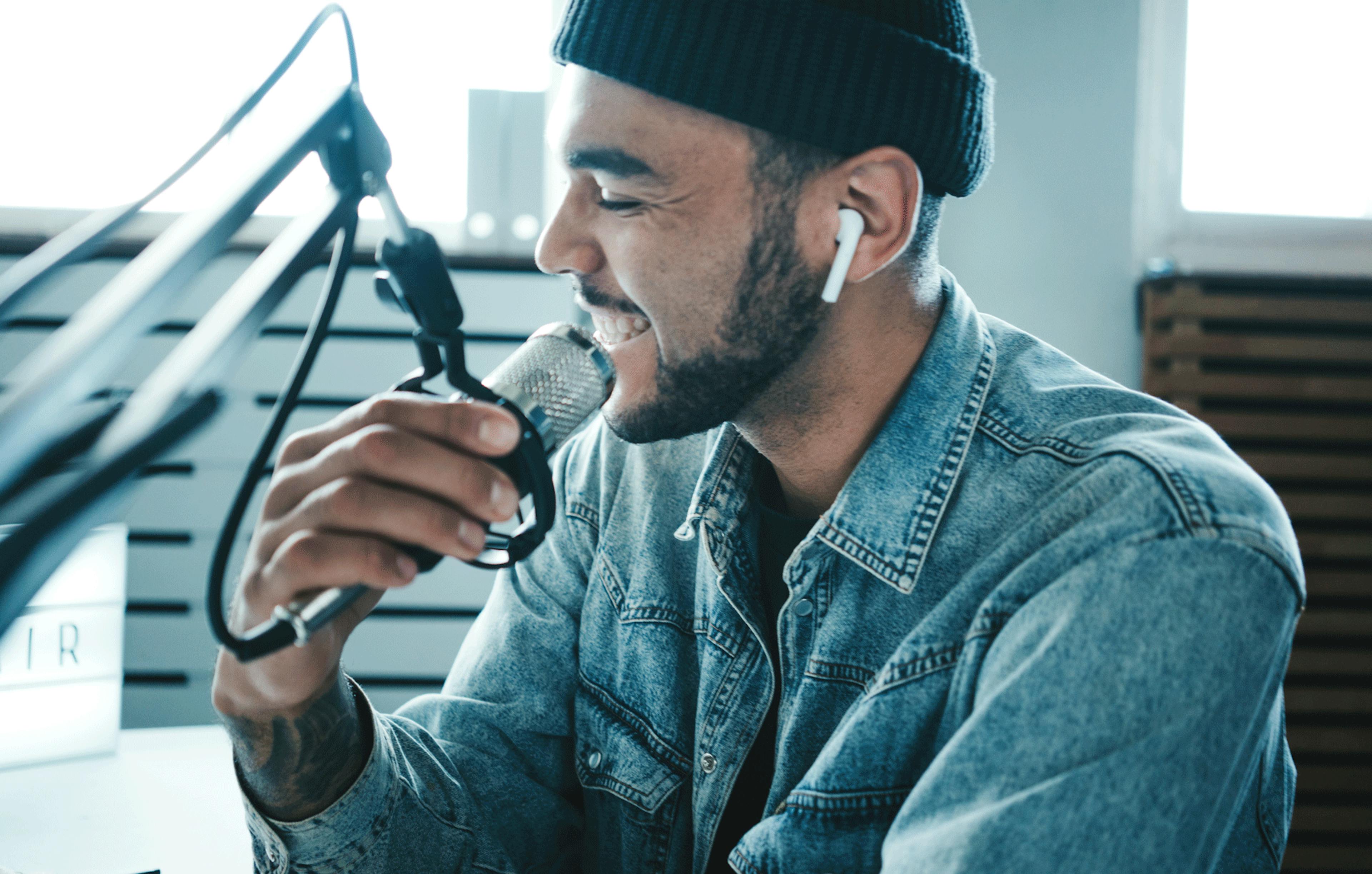 Image of someone speaking into a microphone with Airpods in while recording a podcast