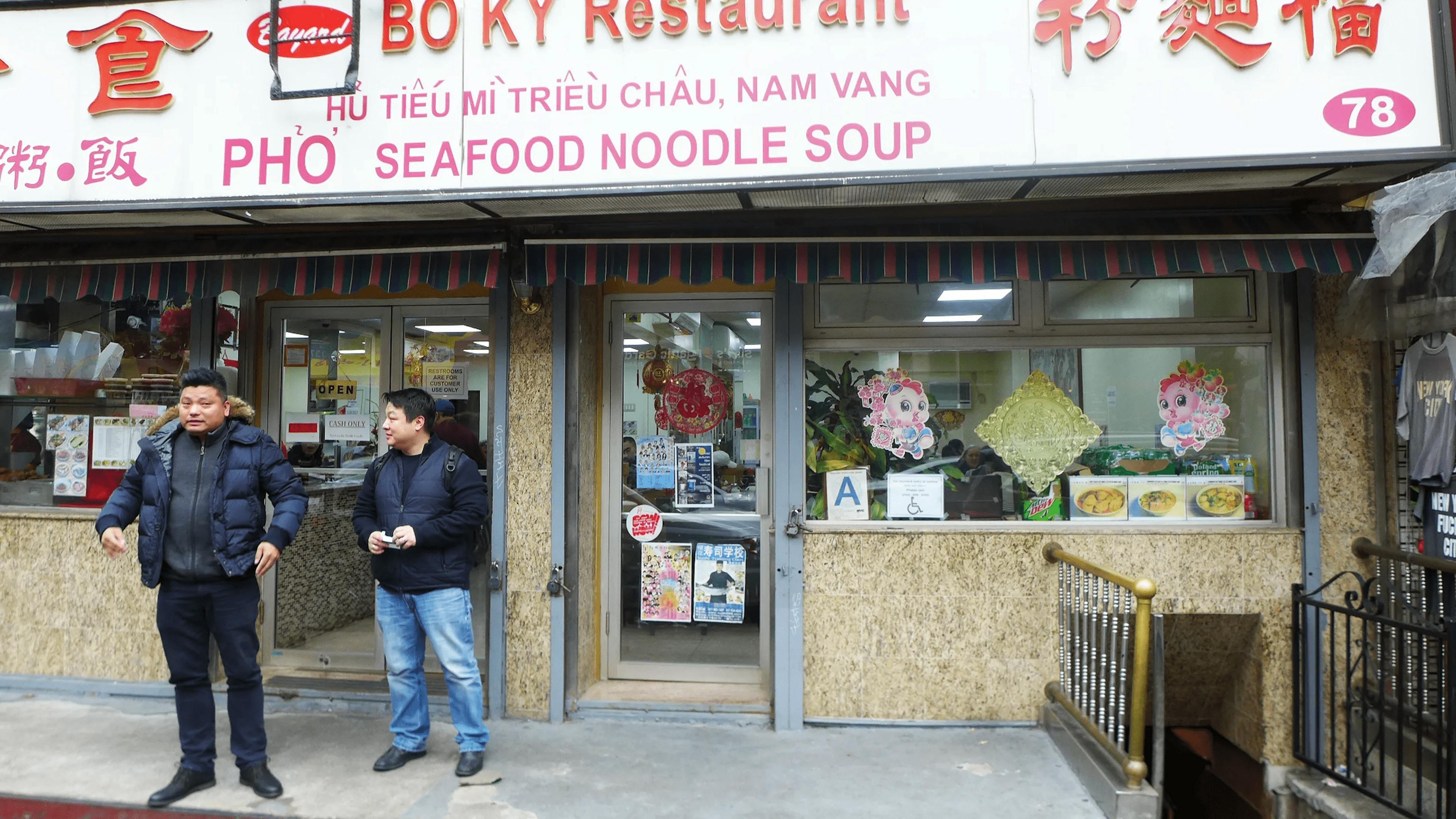 People standing in front of a Pho restaurant.