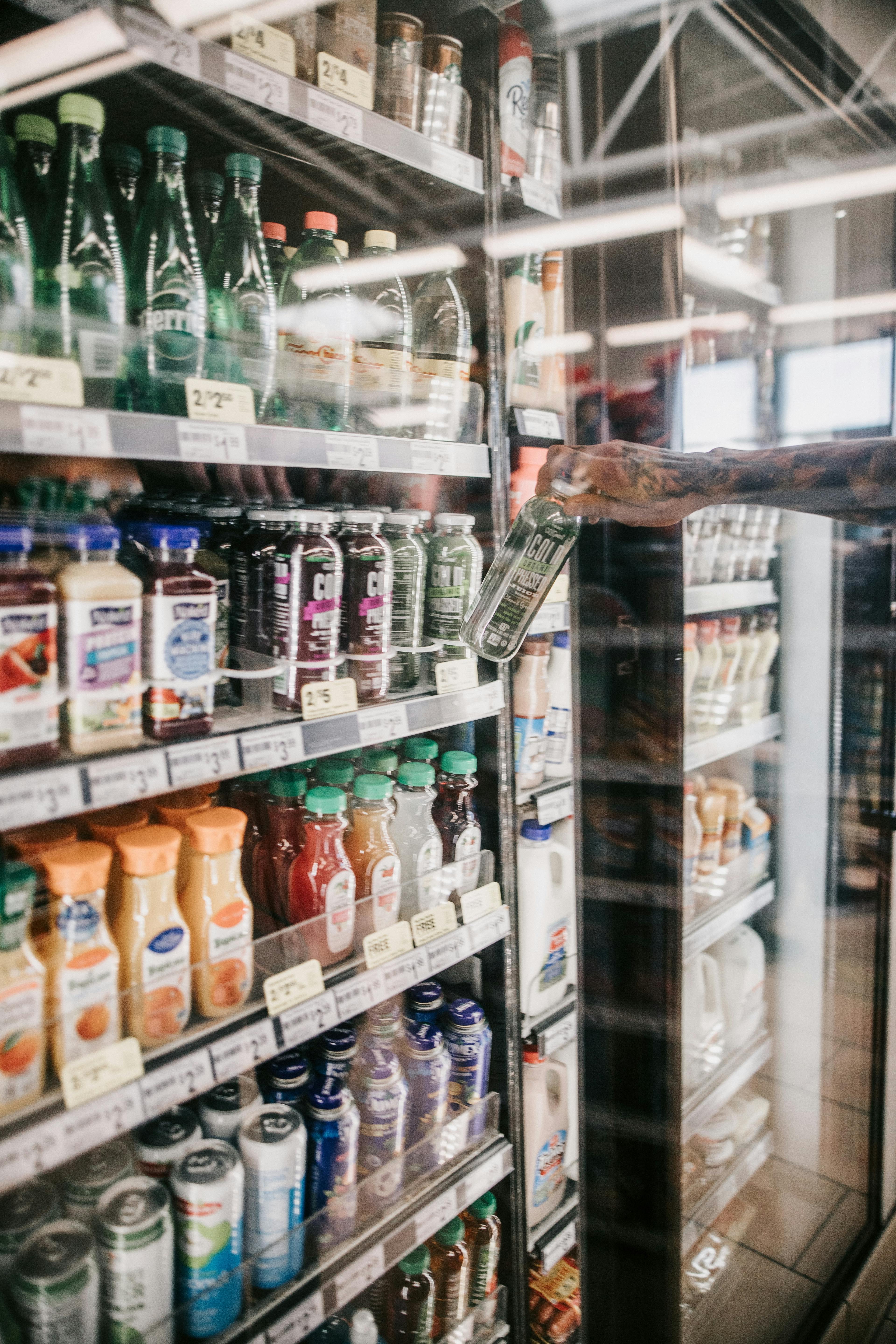 Customer grabbing a cold pressed juice out of the refrigerator at a convenience store