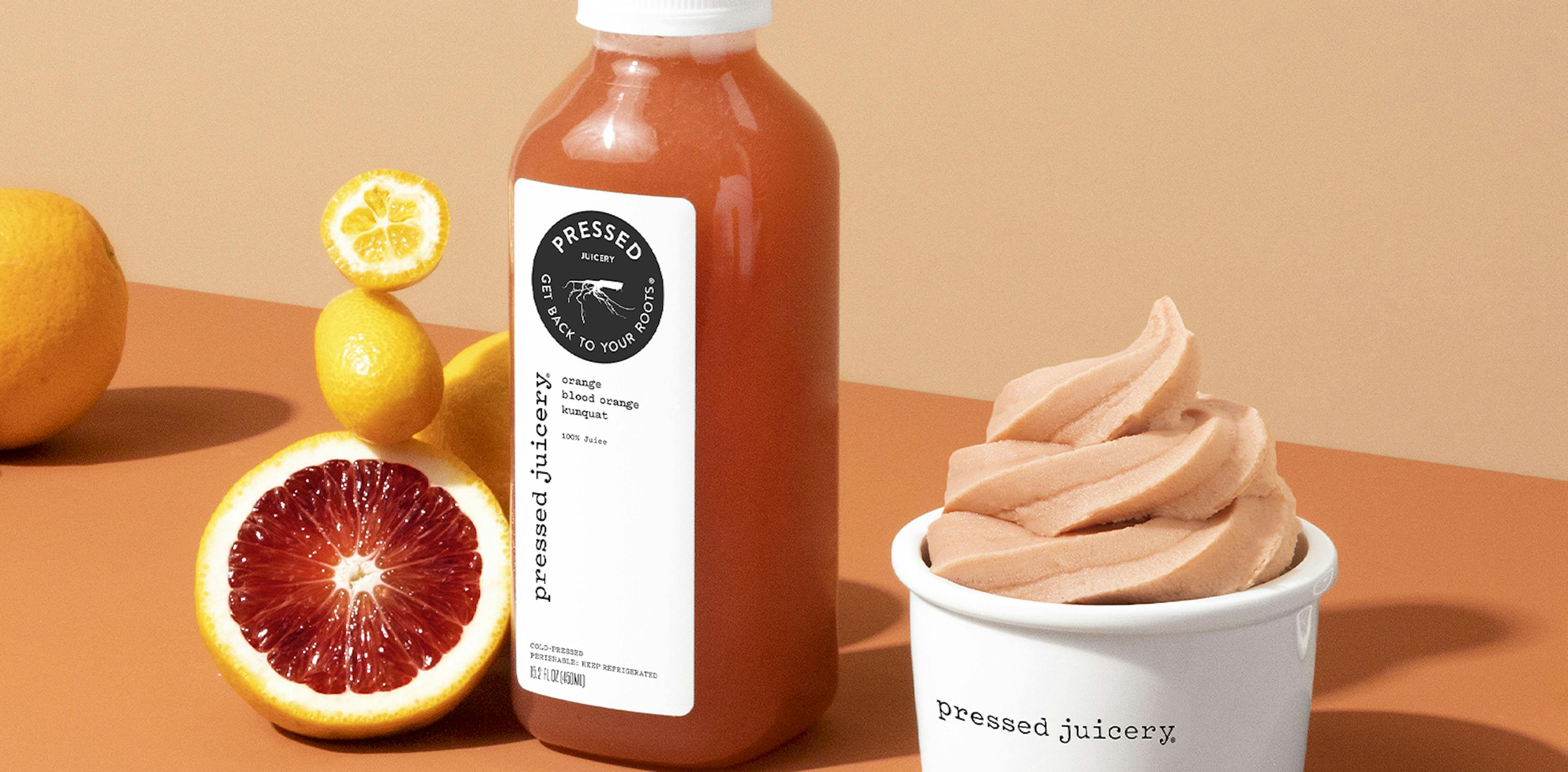 Image of an dark orange pressed juice next to blood oranges on an orange background