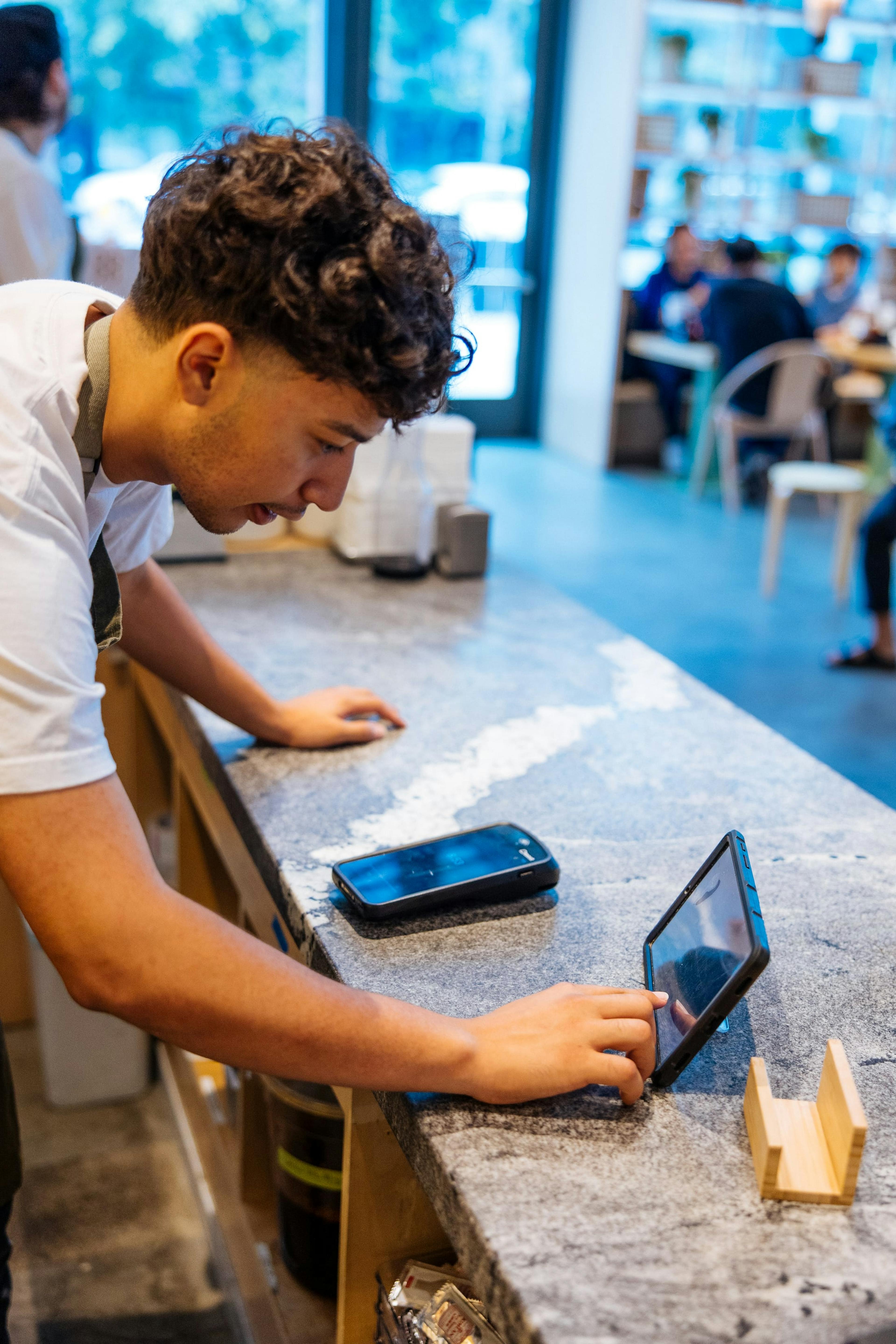 Image of a restaurant employee manages delivery orders from a tablet