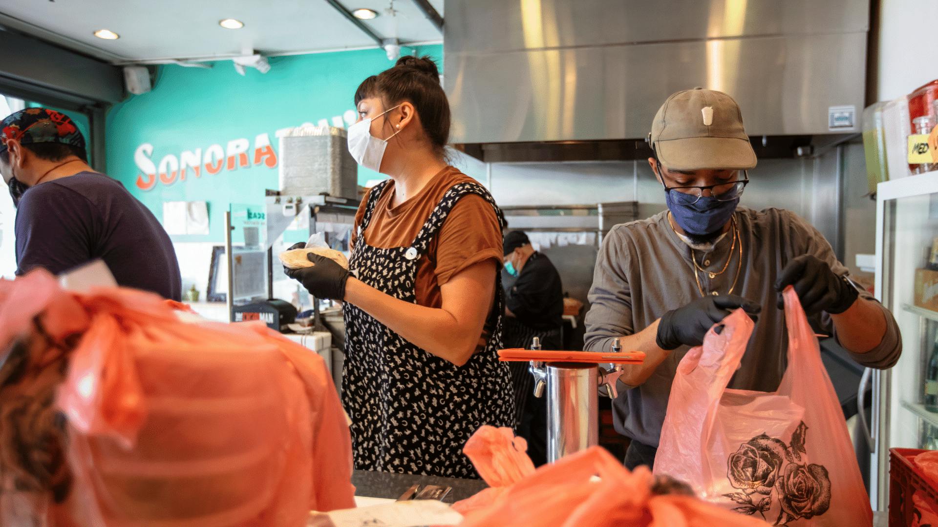 Image of two restaurant staff members packing delivery orders