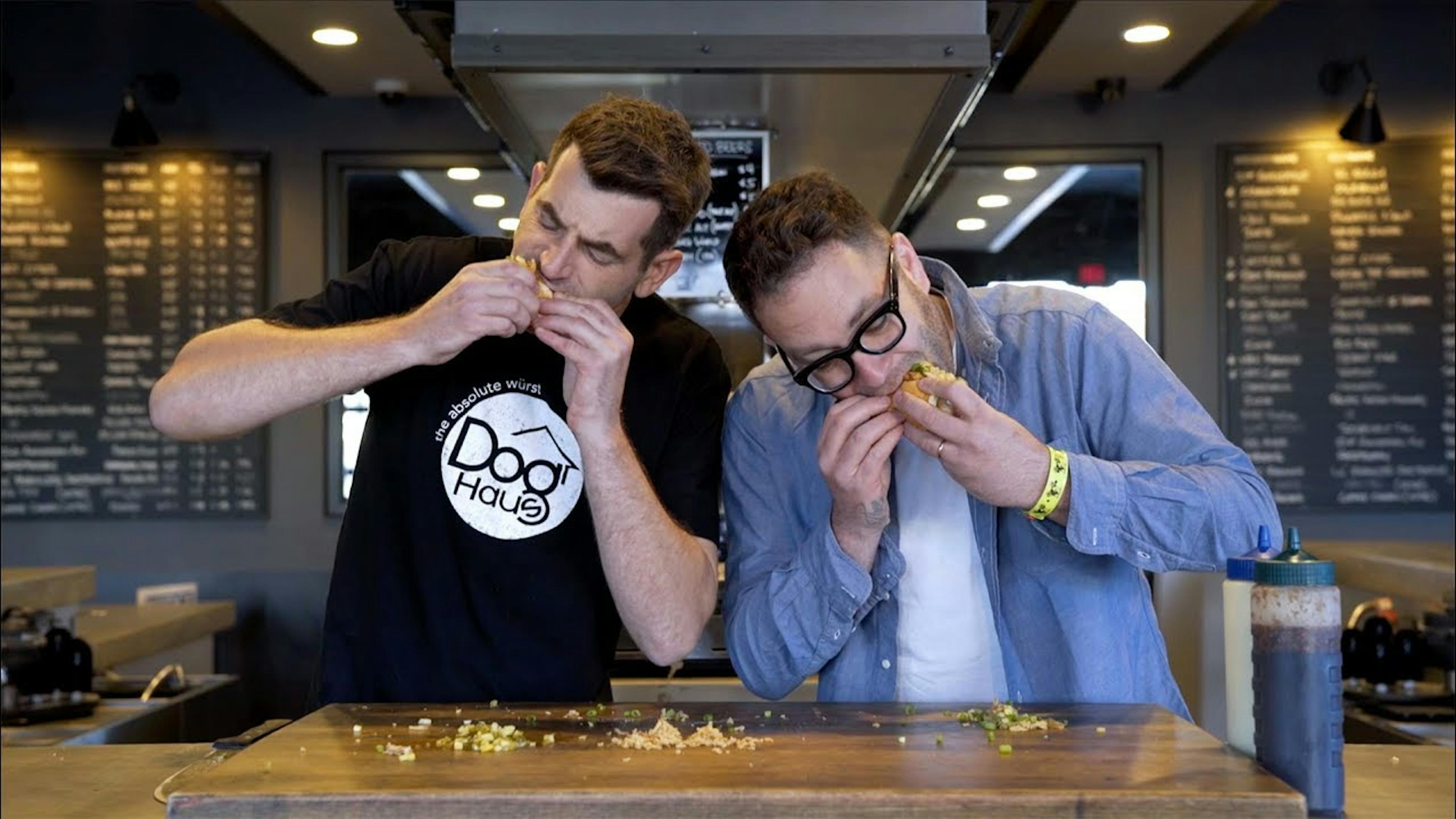 Photo of the culinary director and founder of Dog Haus eating hot dogs in the store