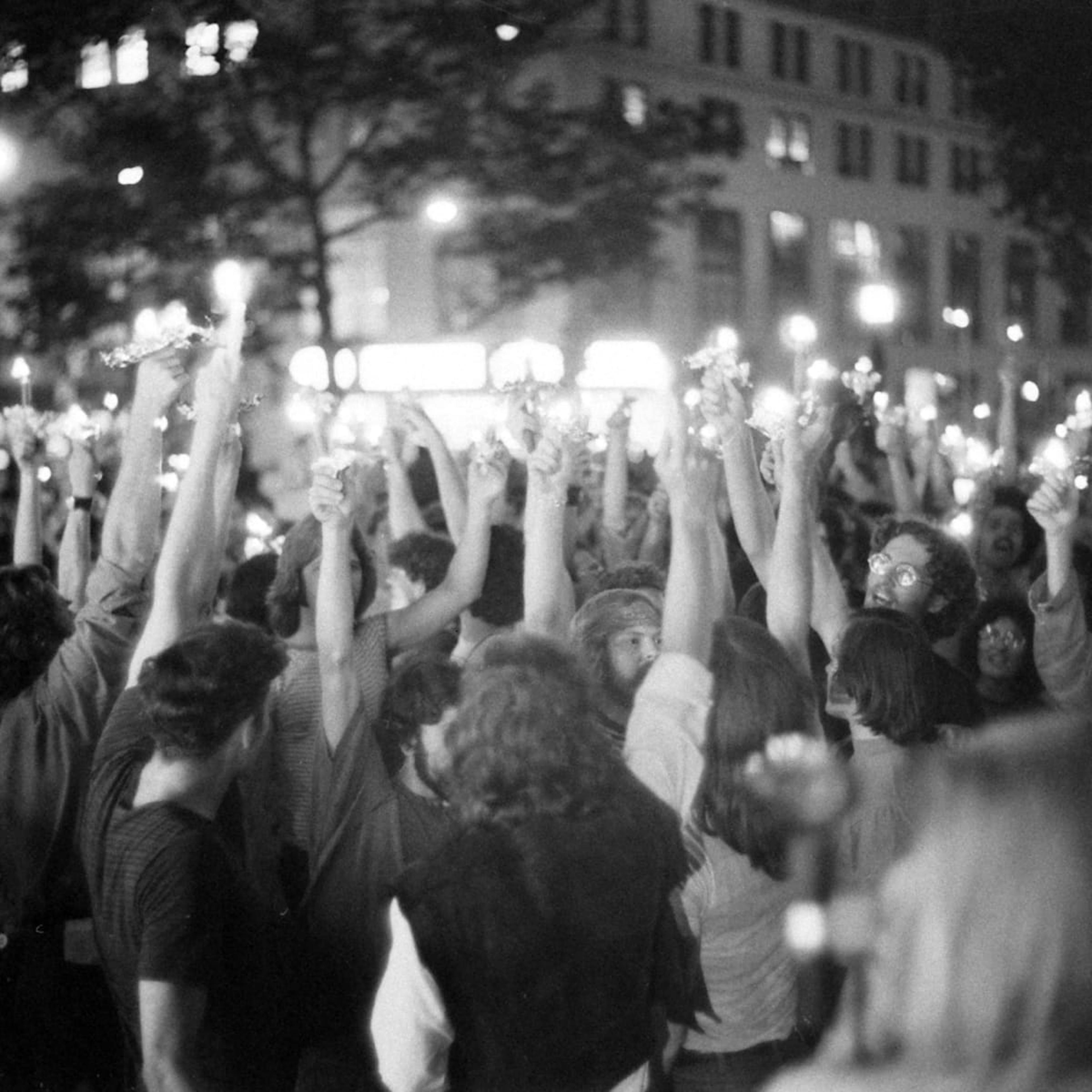 Image of protestors standing packed into a city square with their arms raised