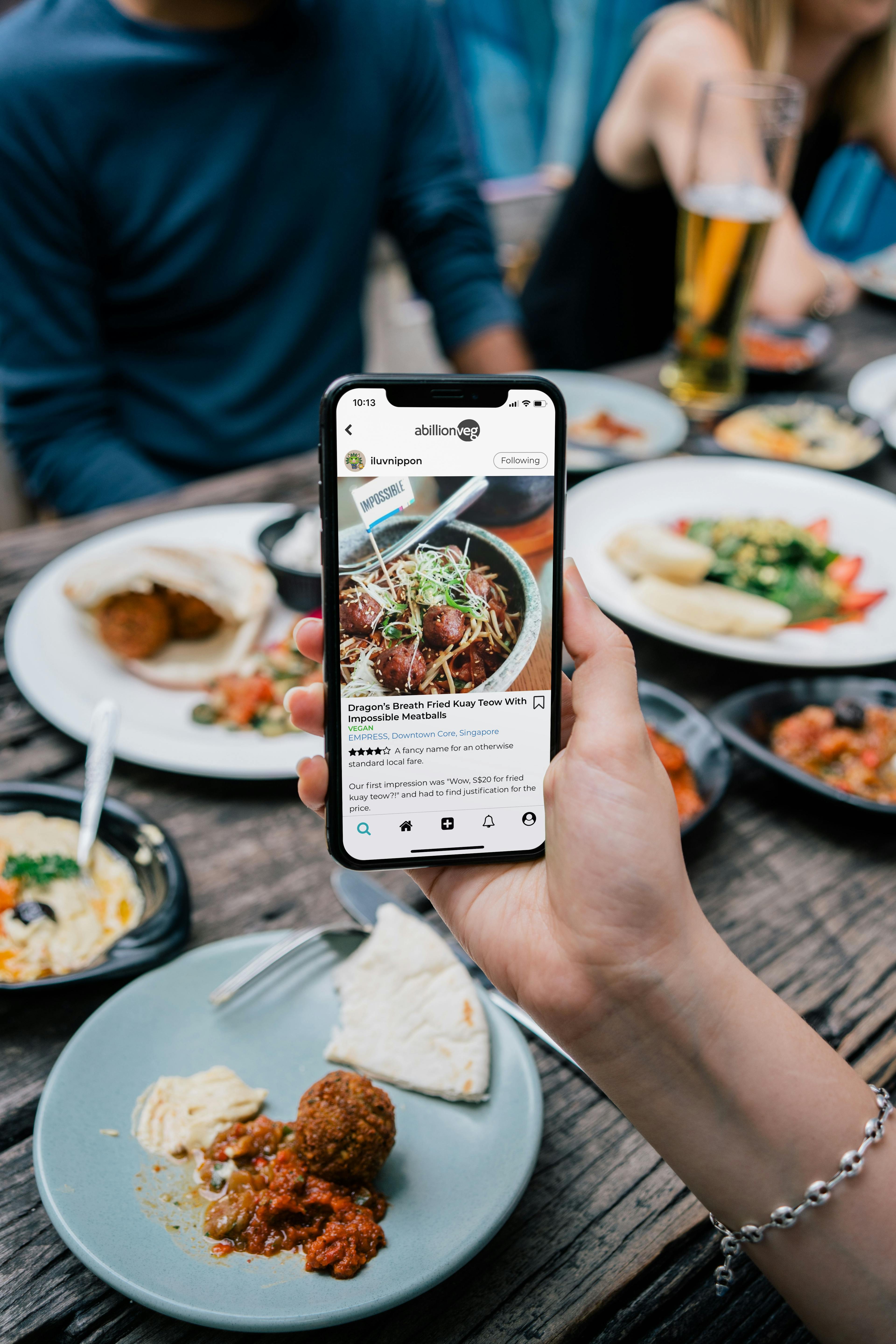 Image of a group of people at a restaurant, one of whom is writing a review about that restaurant online