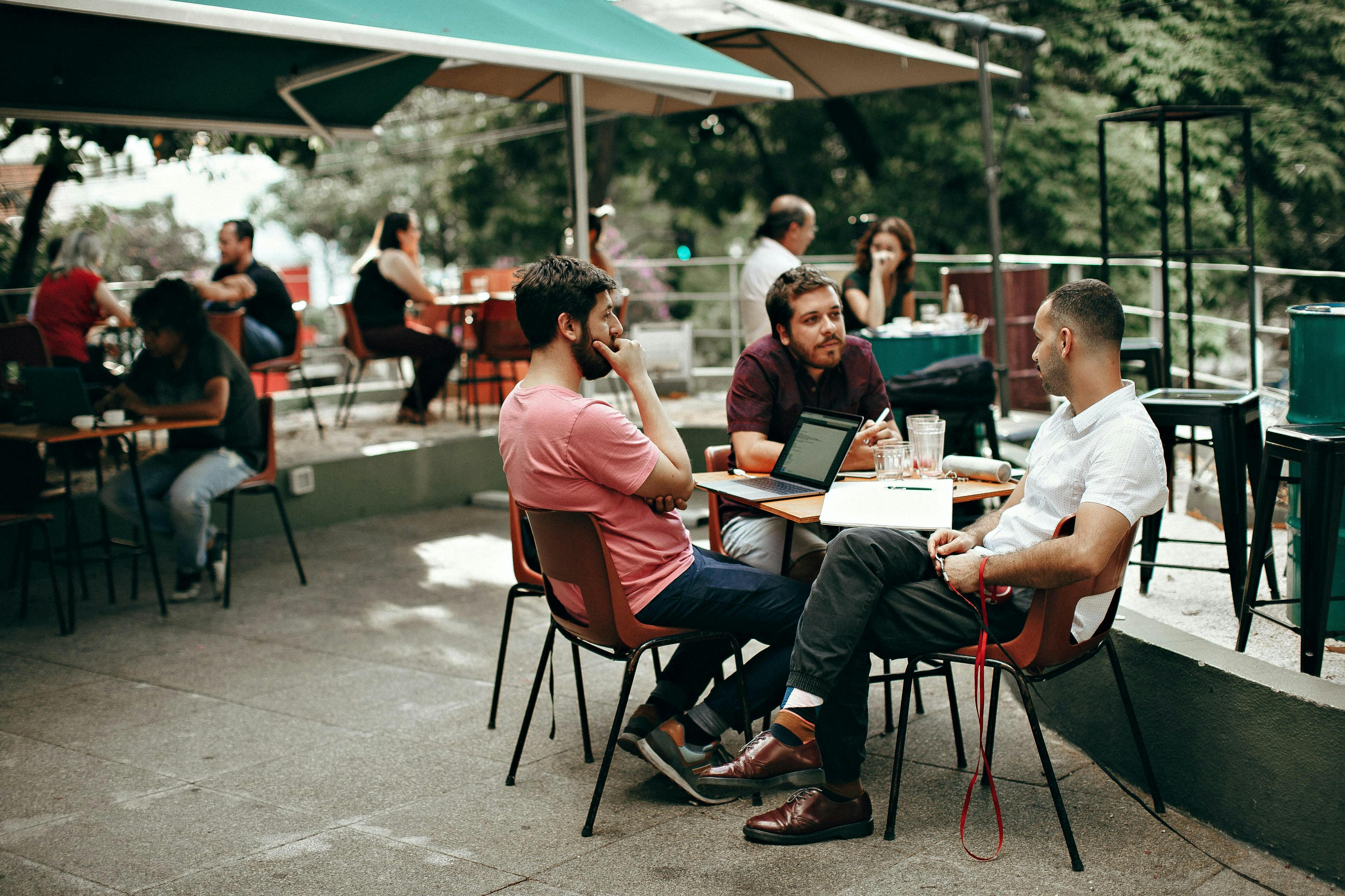 Image of three gentleman chatting on a restaurant patio