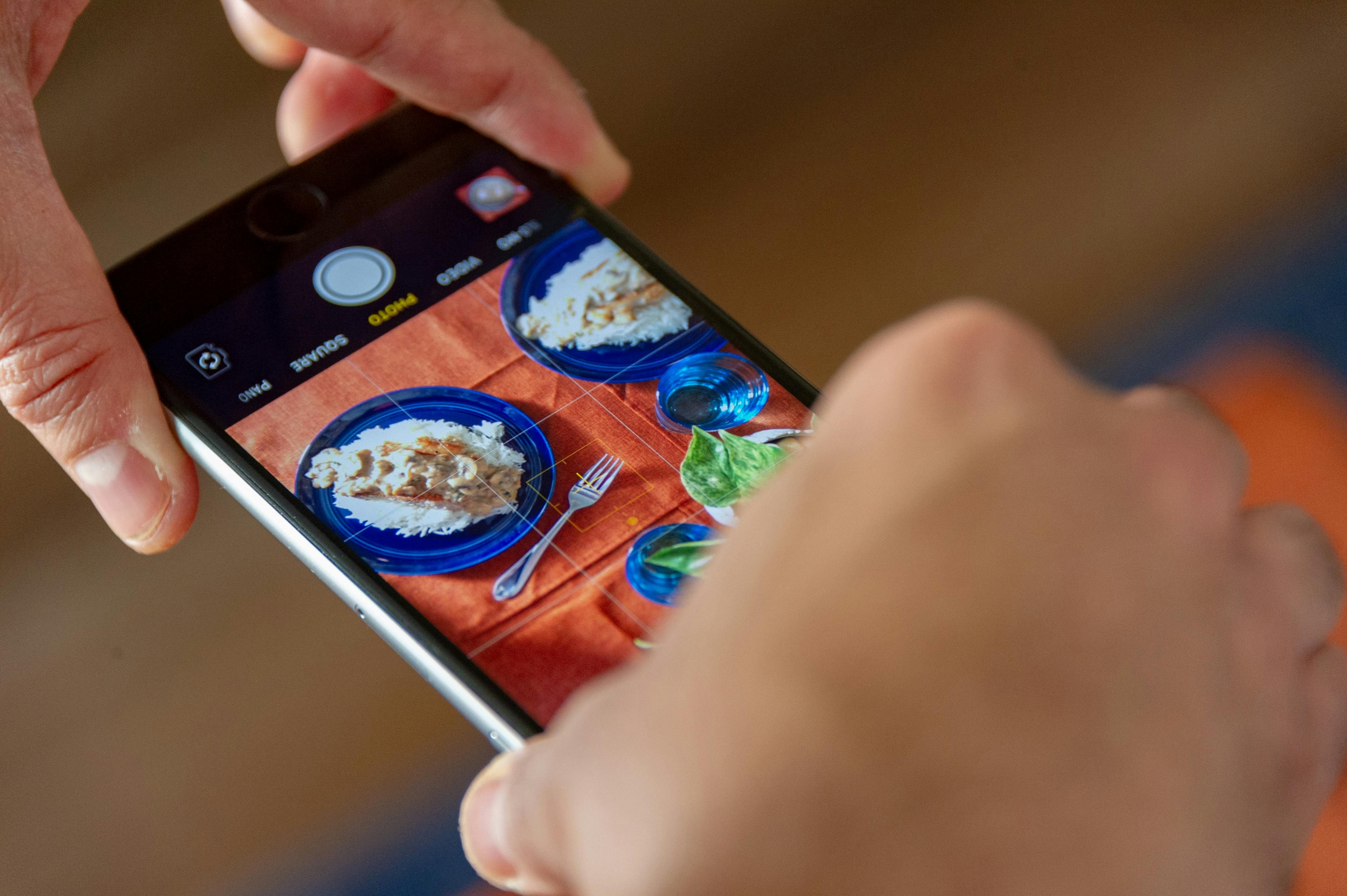 Image of someone taking a photo of food from their iPhone