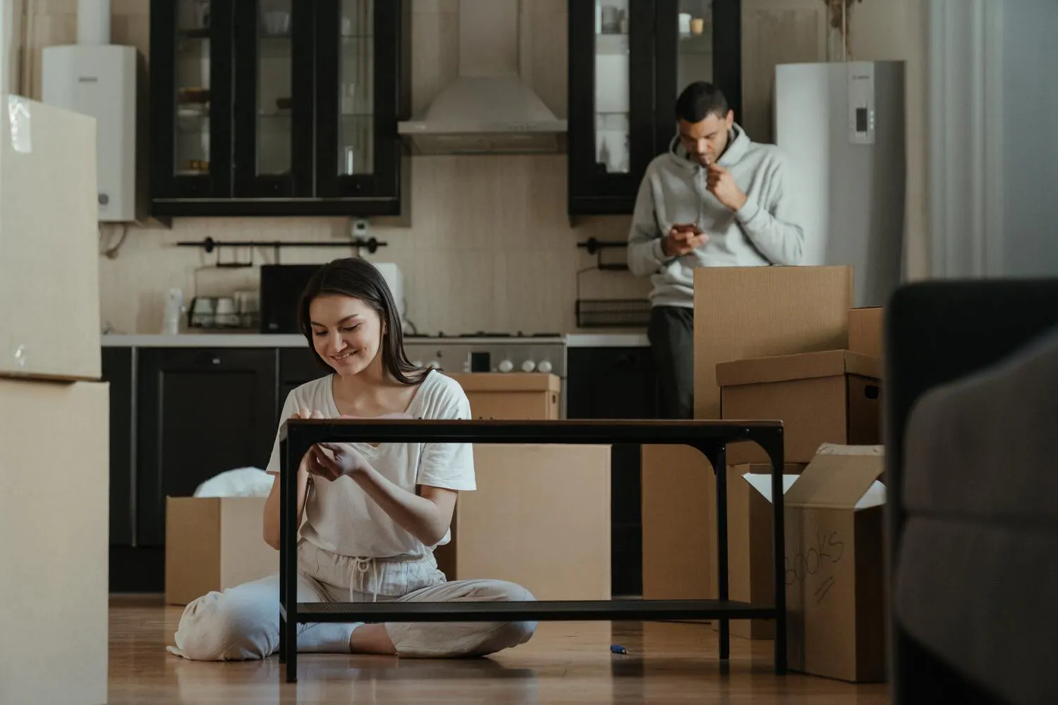 Femme assise au sol entourée de cartons 
