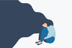 Kona með sítt hár situr ein á gólfi.