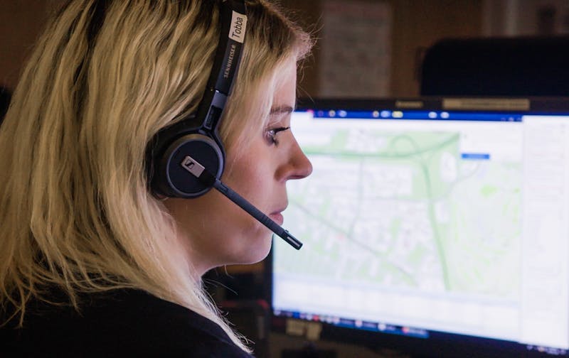 Neyðarvörður með heyrnatól og míkrófón. Í bakgrunni sést skjár með landakorti.