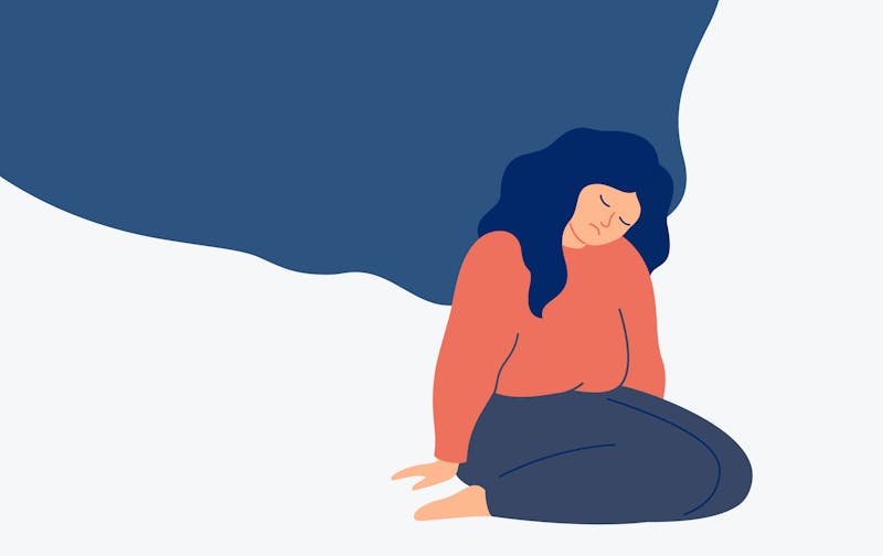 Manneska situr á hnjánum á gólfinu. Hún er leið á svip, með lokuð augun og höfuðið lítur niður til jarðar.