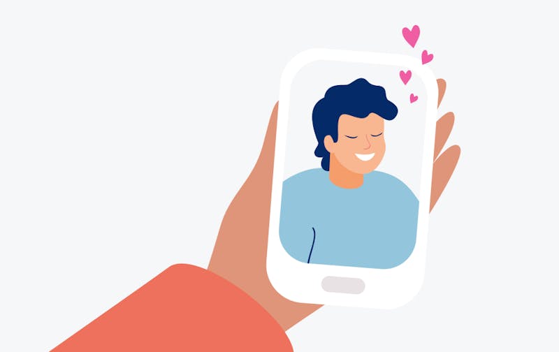 Hönd holdur um síma með mynd af strák og hjörtu fljúga upp