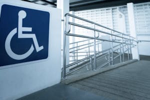 Merki fyrir fatlaða á vegg fyrir ofan skábraut.