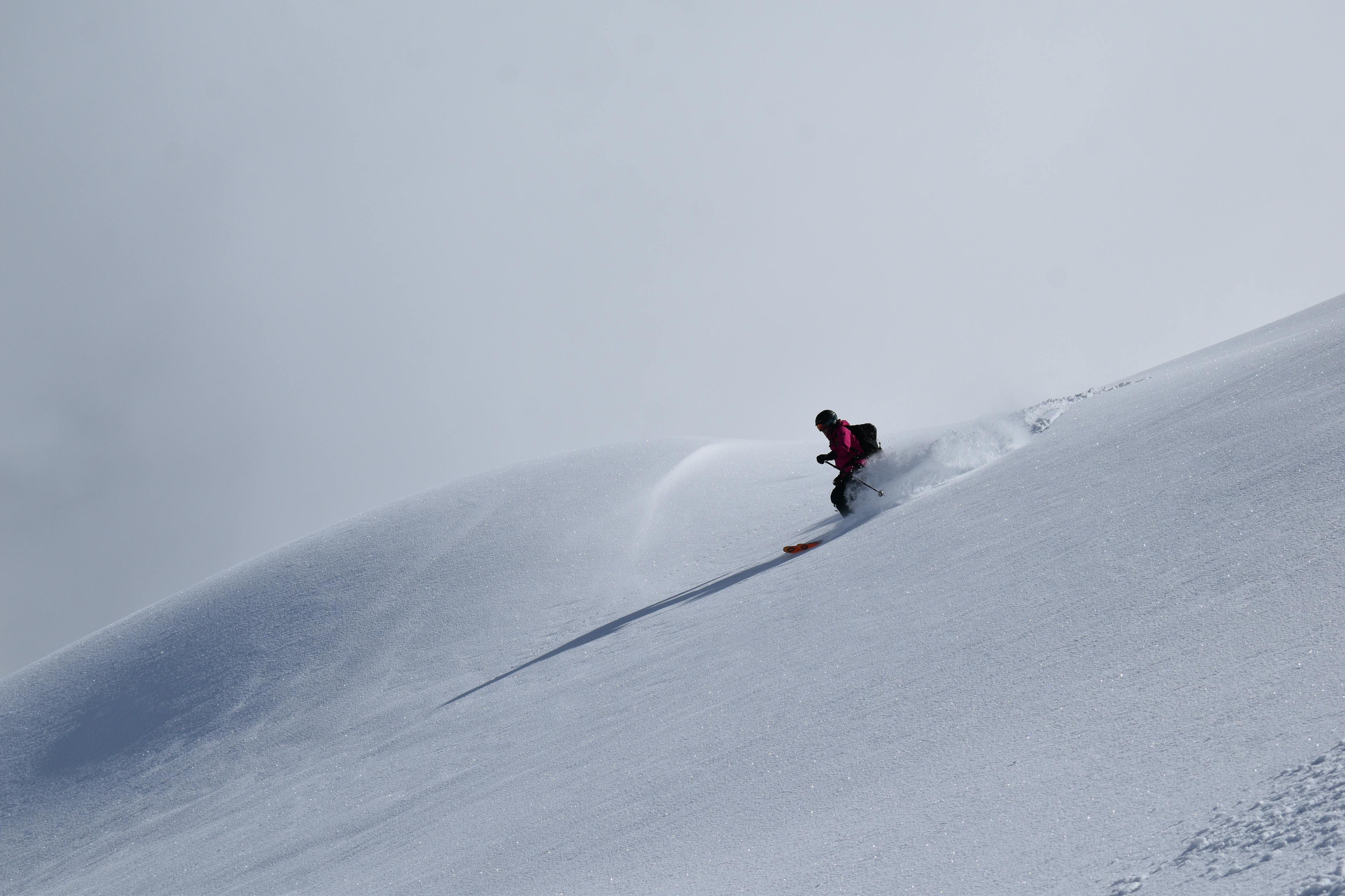 Skiier descending a powder field. 