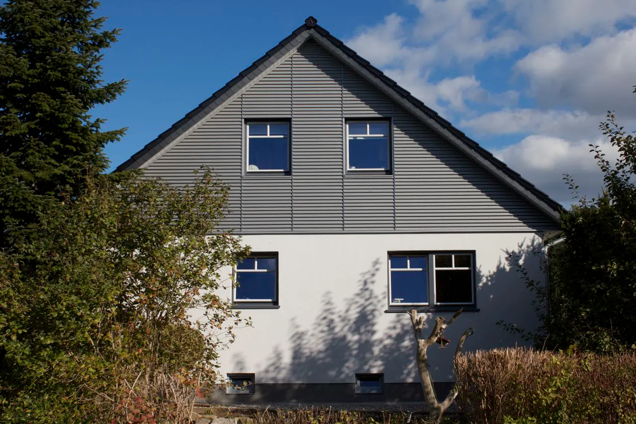 Geschwungene Außenfensterbänke SLB 590 an einer verputzen Hausfassade mit oberer Holzverkleidung