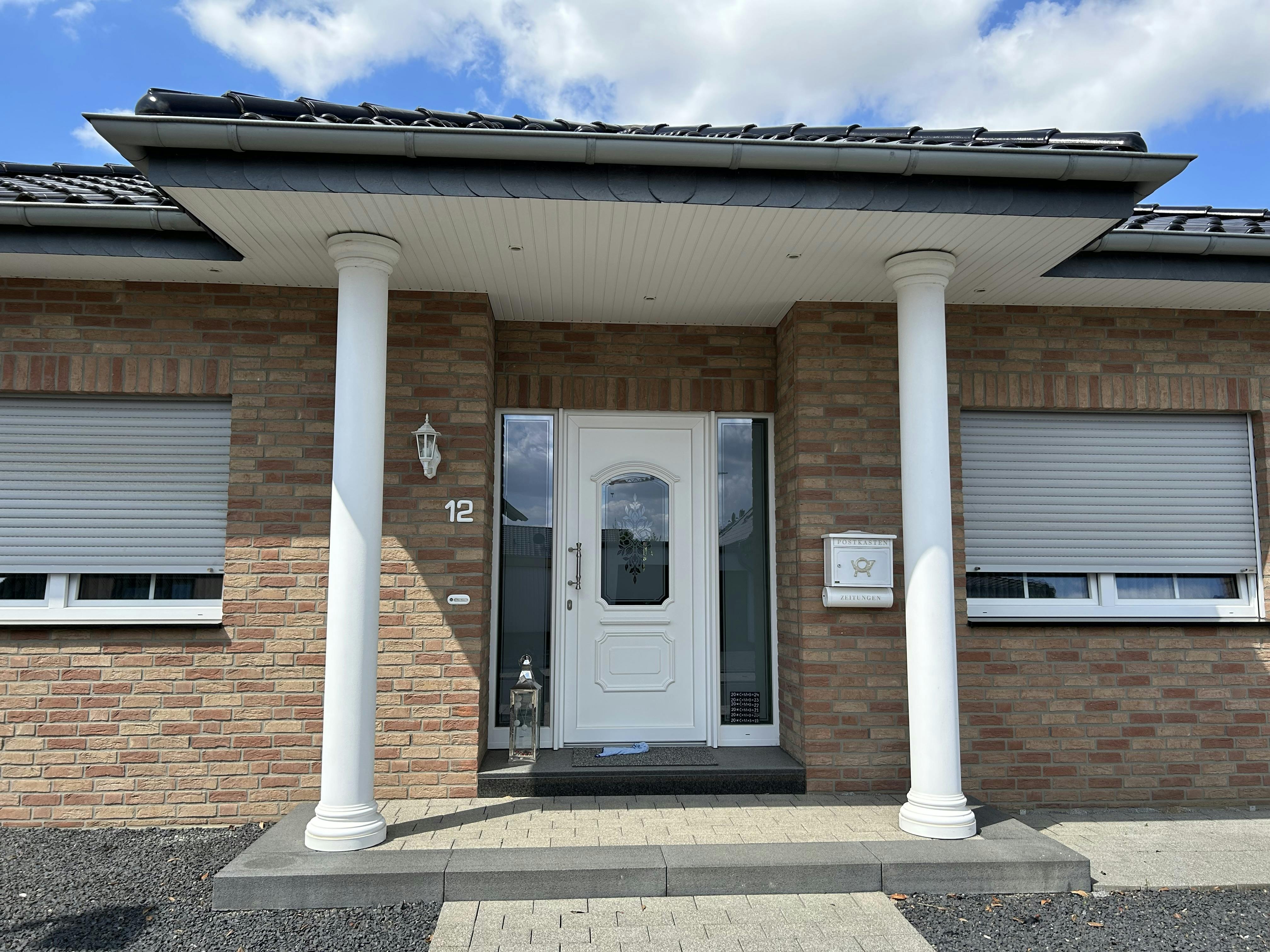 Hauseingang mit zwei Betonsäulen unter einem Vordach