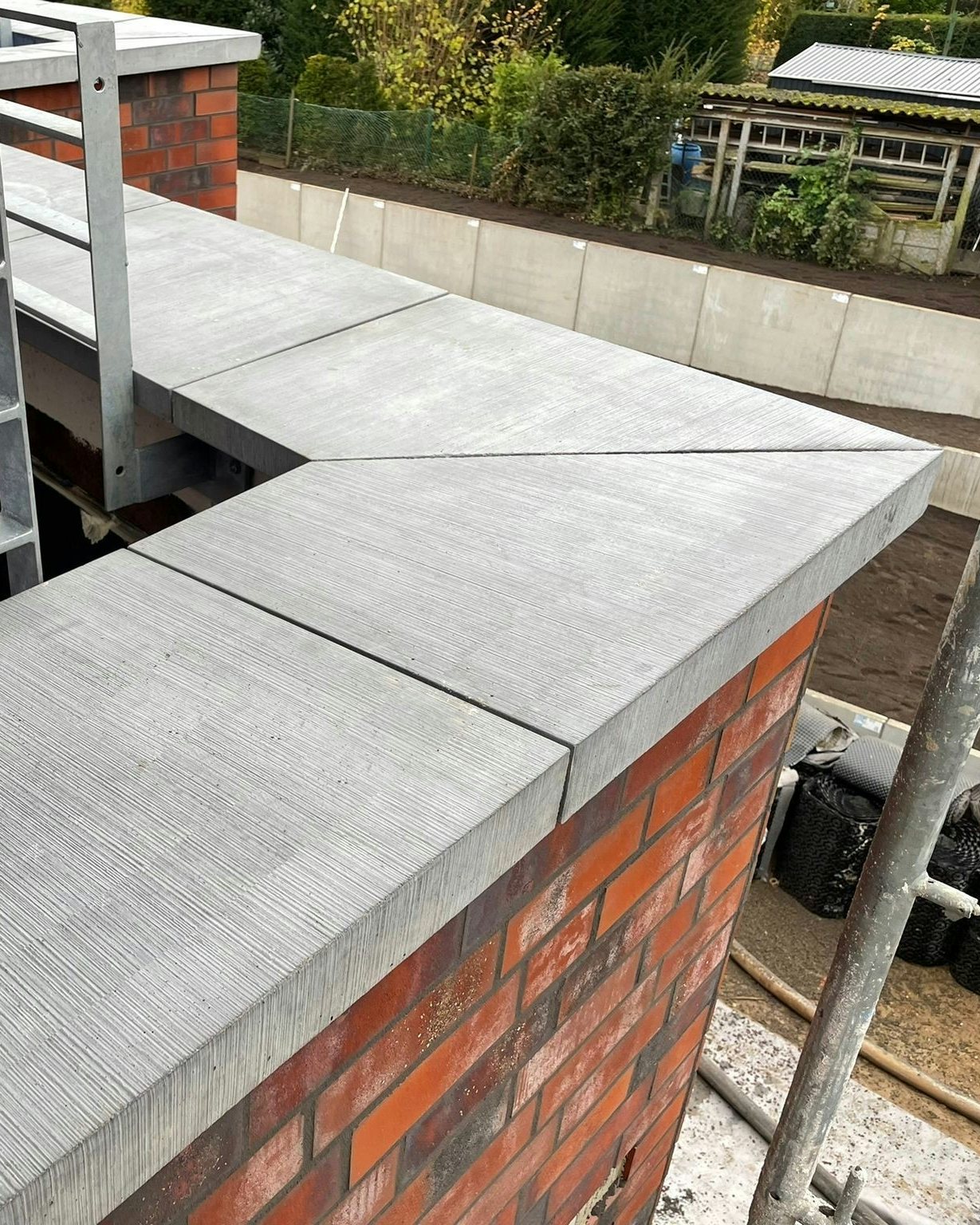 Pultdachförmige Mauerabdeckung von Niessen Beton über Eck