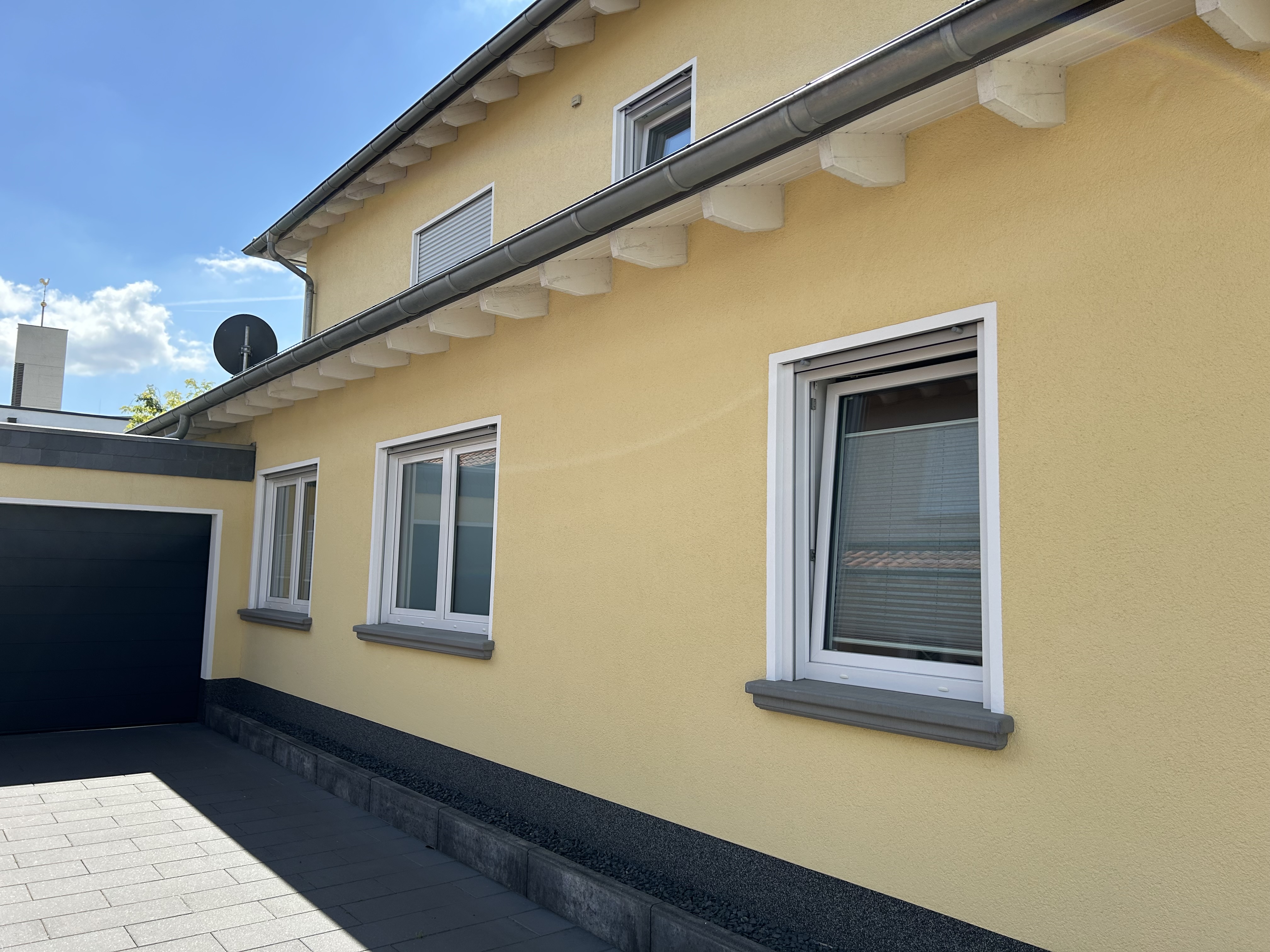 Gelbe Putzfassade mit anthrazit gestrichenen Außenfensterbänken WSB 200