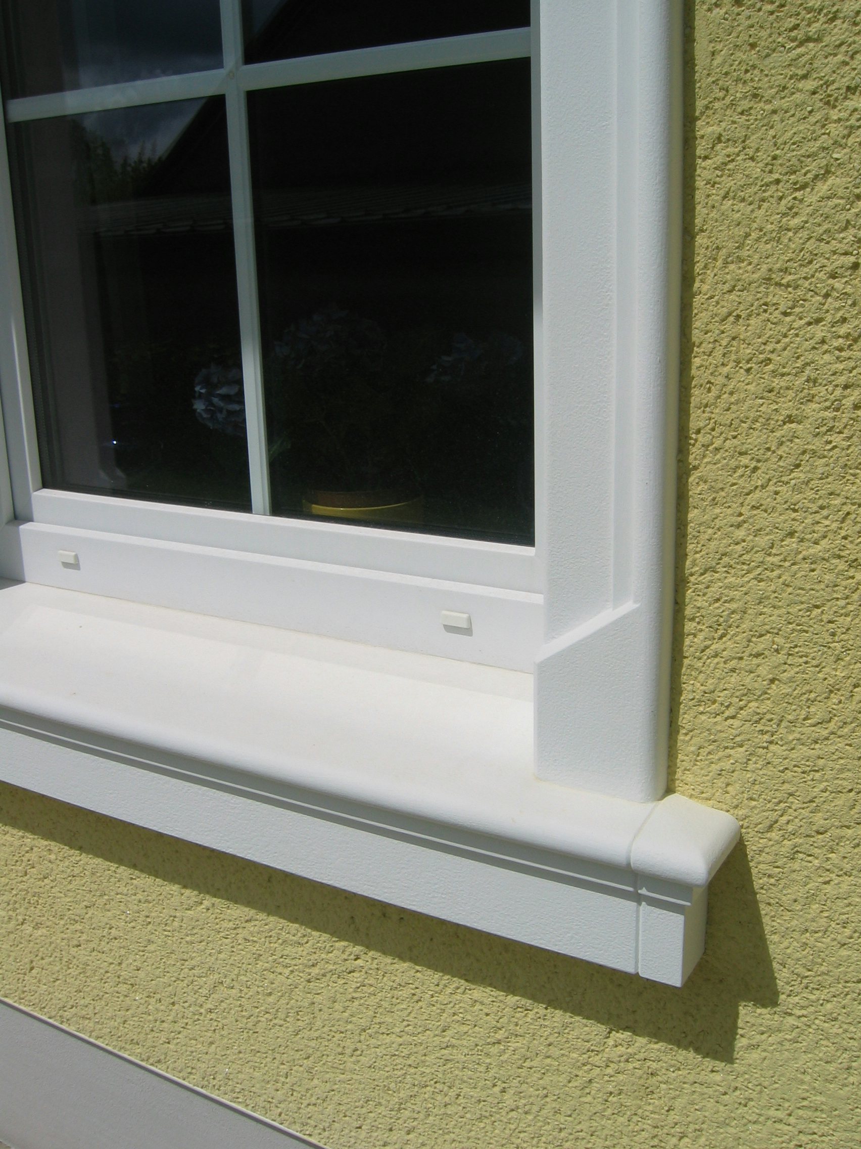 Klassische Betonfensterbank an einer gelben Putzfassade