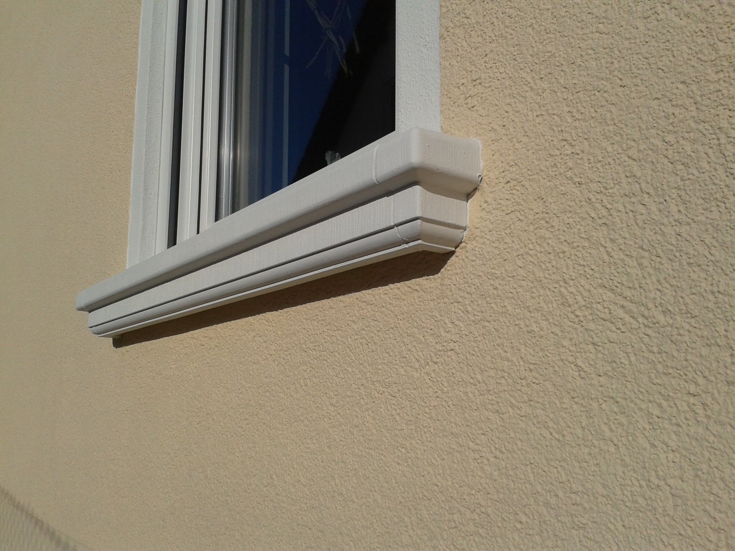 Formschöne Außenfensterbank SLB 200 aus Beton an gelb verputzter Hauswand