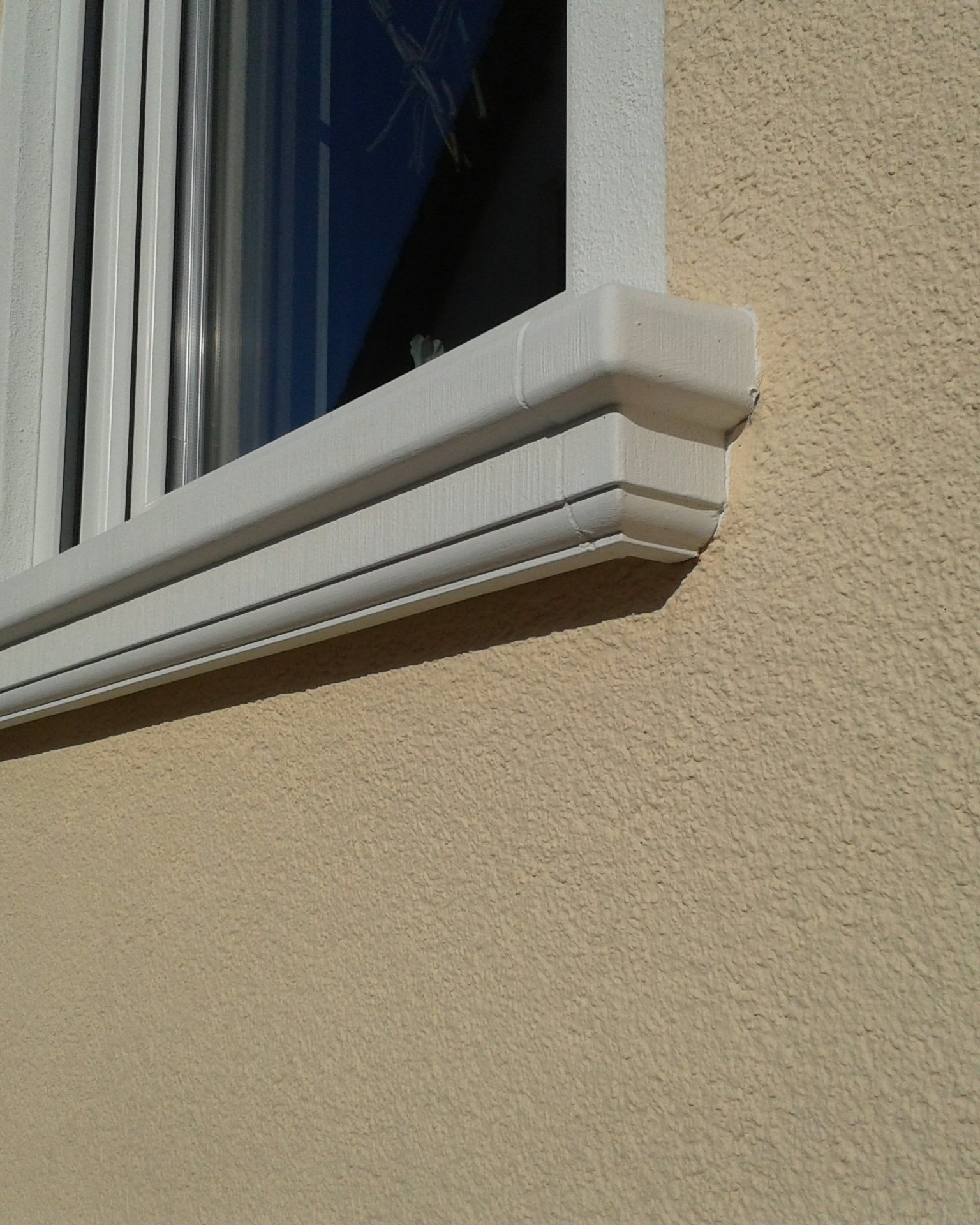 Formschöne Außenfensterbank SLB 200 aus Beton an gelb verputzter Hauswand