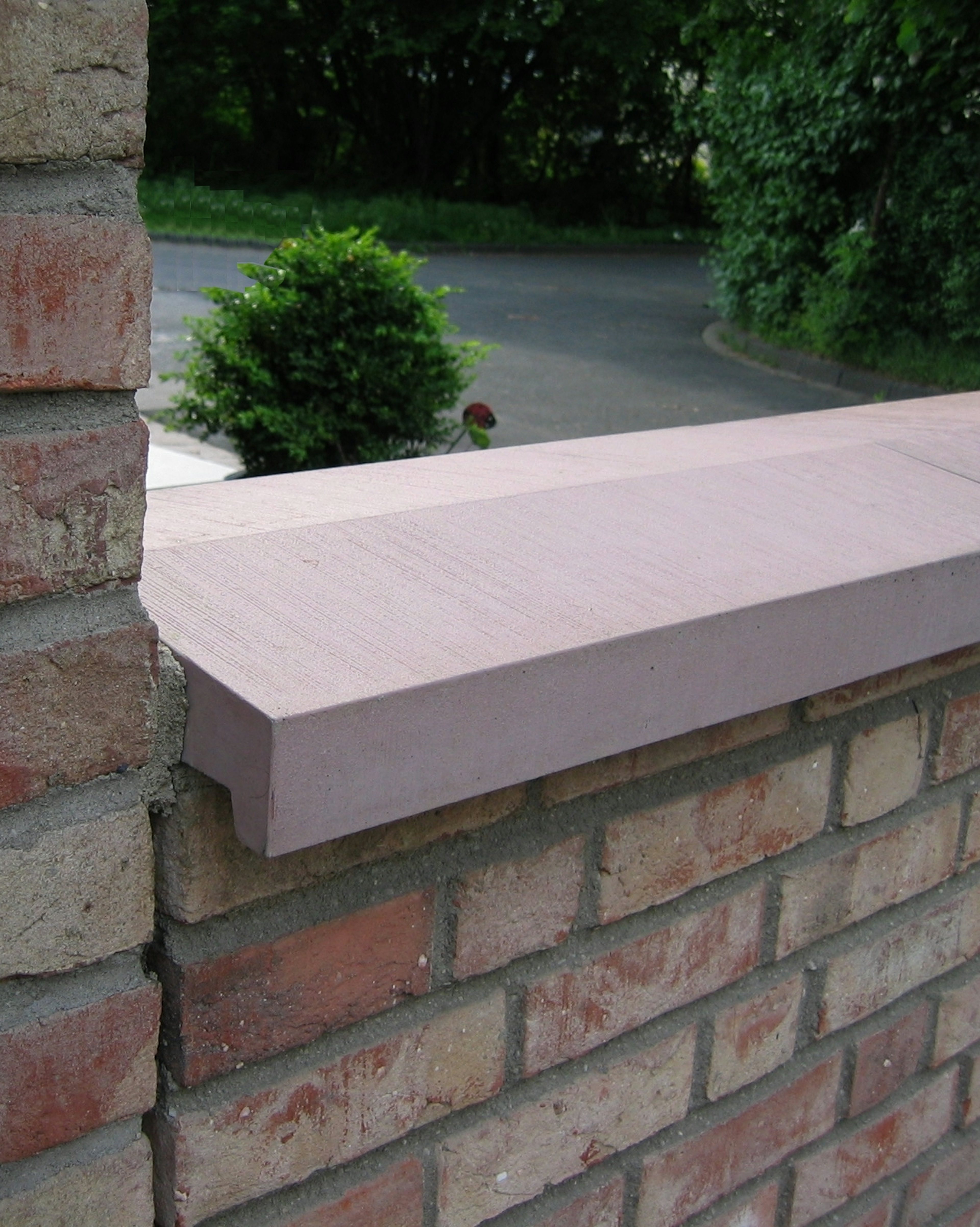 Mauerabdeckung MAD Satteldach  toskana-rot auf einer roten Klinkermauer