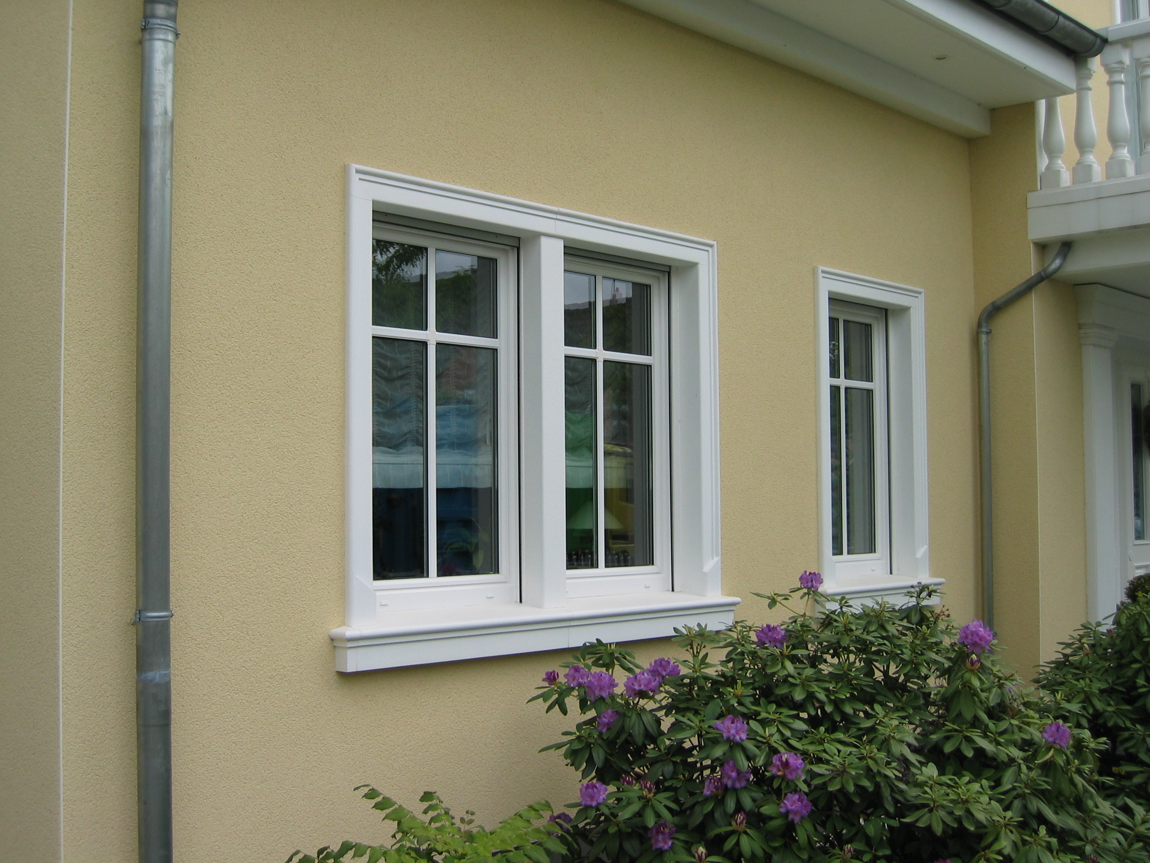 Gelb verputzte Hausfassade mit Fensterbänken SLB 100 und Winkelgewänden SLG 100 als Fensterumrahmungen