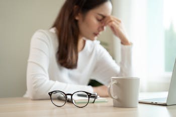 眼鏡を外し、疲れたように目をこすっている女性