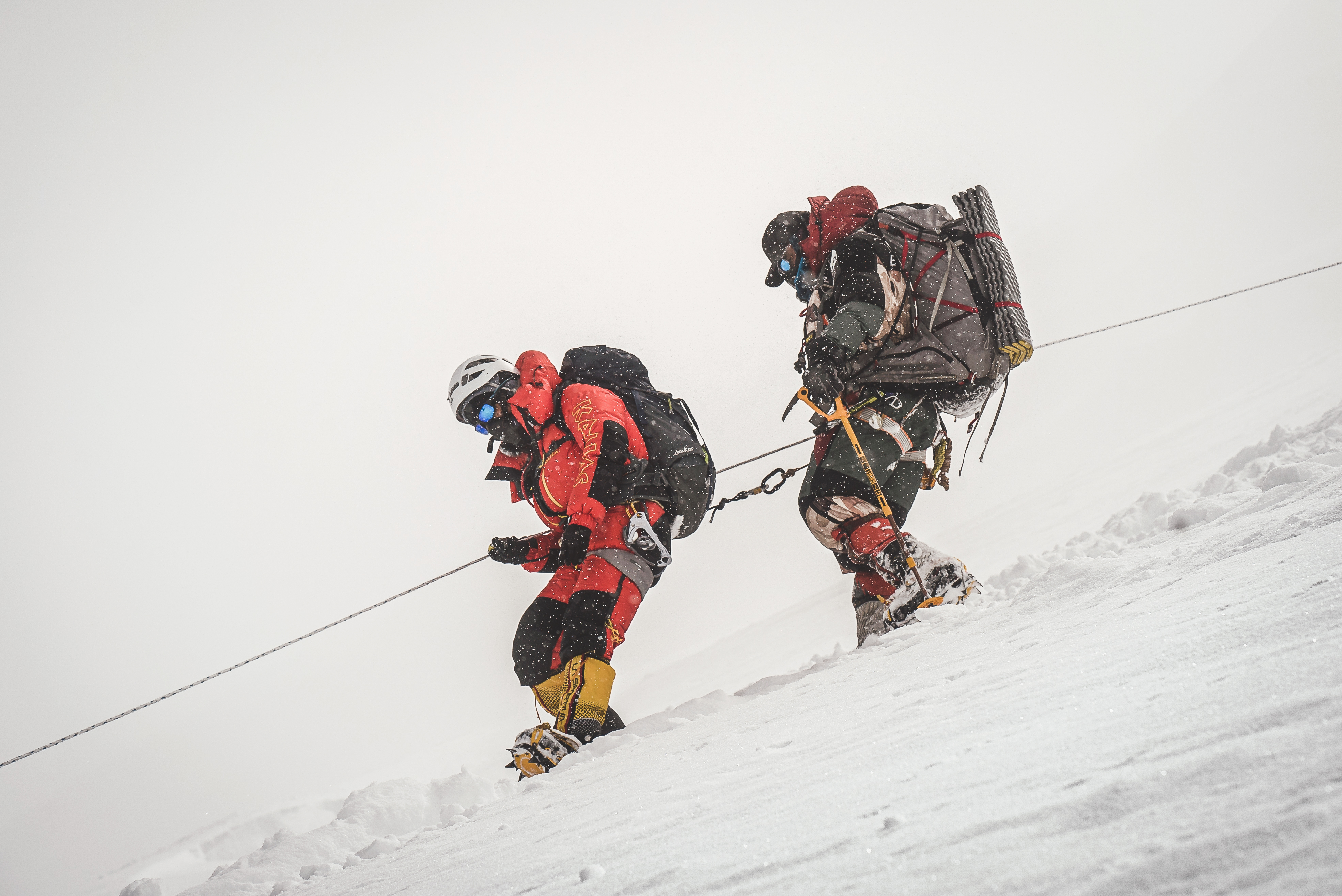 Nims clipped to his client and rope descend the mountain