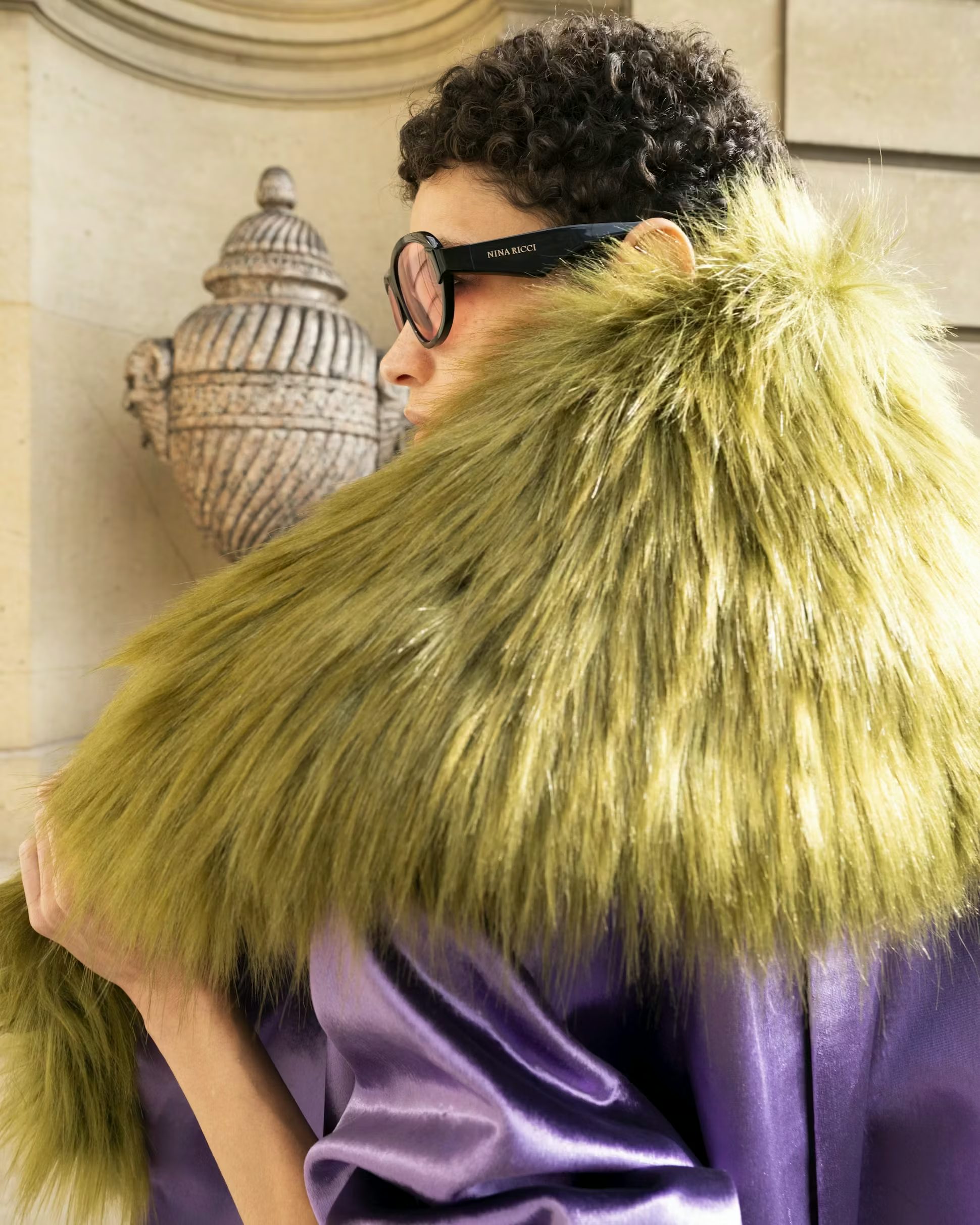 Model posing with a velvet purple coat and green fur backstage at the Fall Winter 2025 show