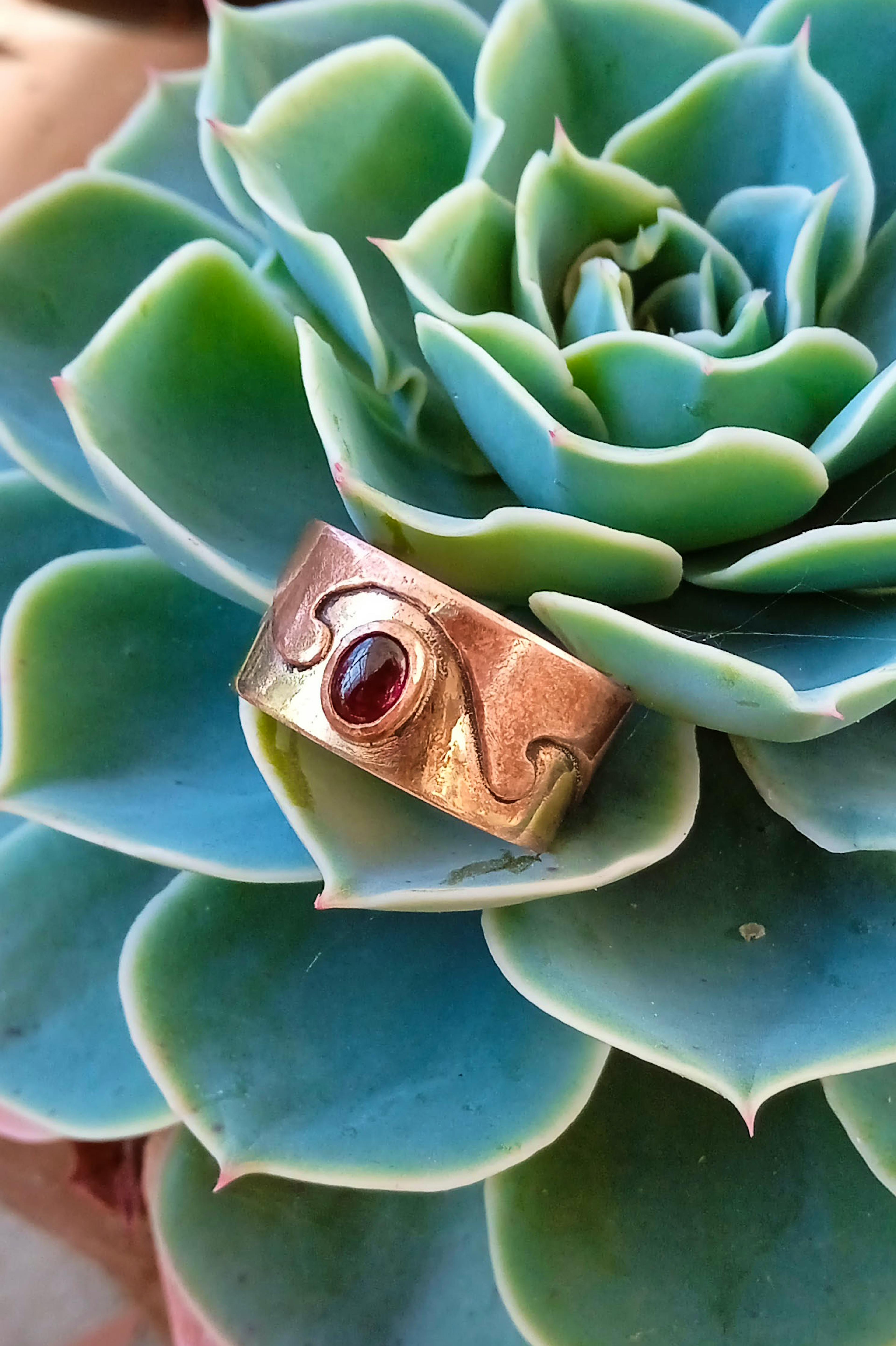 bague laiton cuivre grenat posée sur une racine