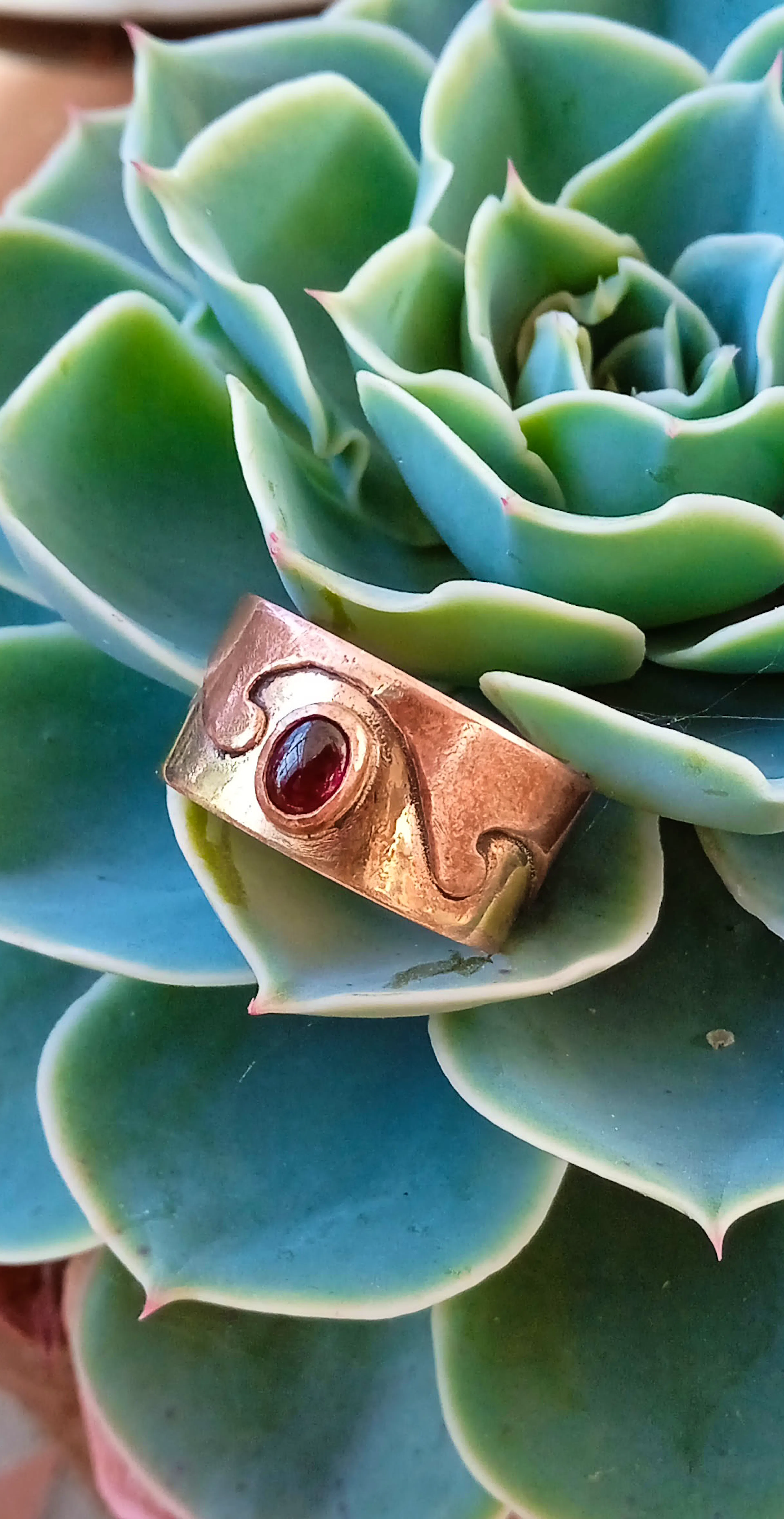 bague laiton cuivre grenat posée sur une racine