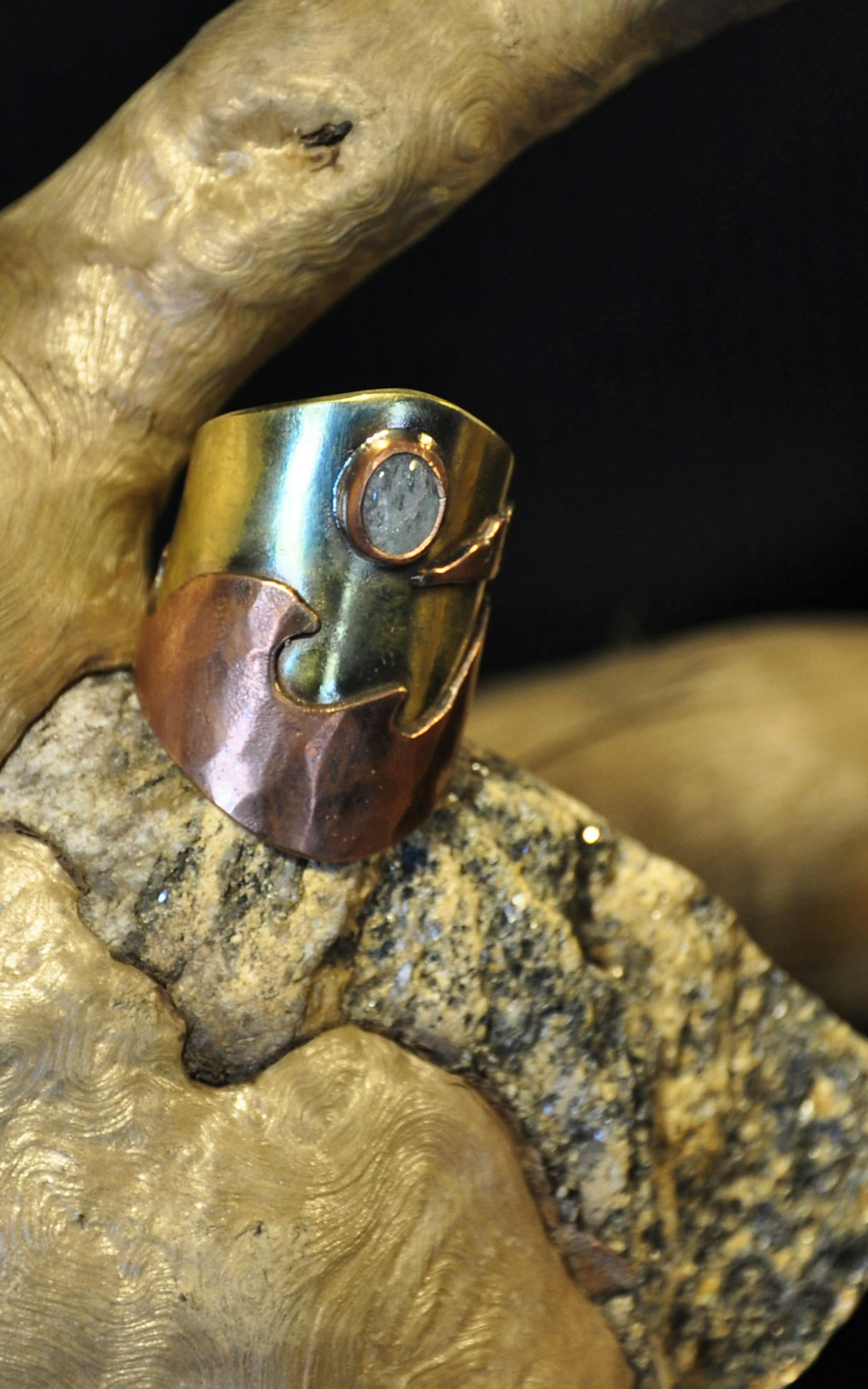 Bague cuivre laiton posée sur une racine cailoux