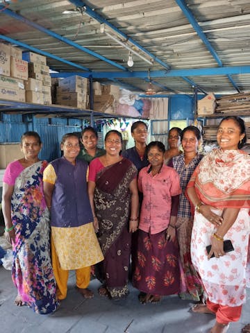 Smiling women standing in a candle packing factory
