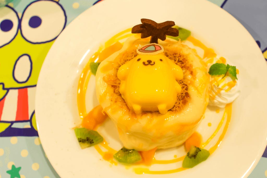 A cute dessert with the character Pompompurin on top on a table featuring another character at the Pompompurin Cafe, one of the Harajuku cafes featuring characters.
