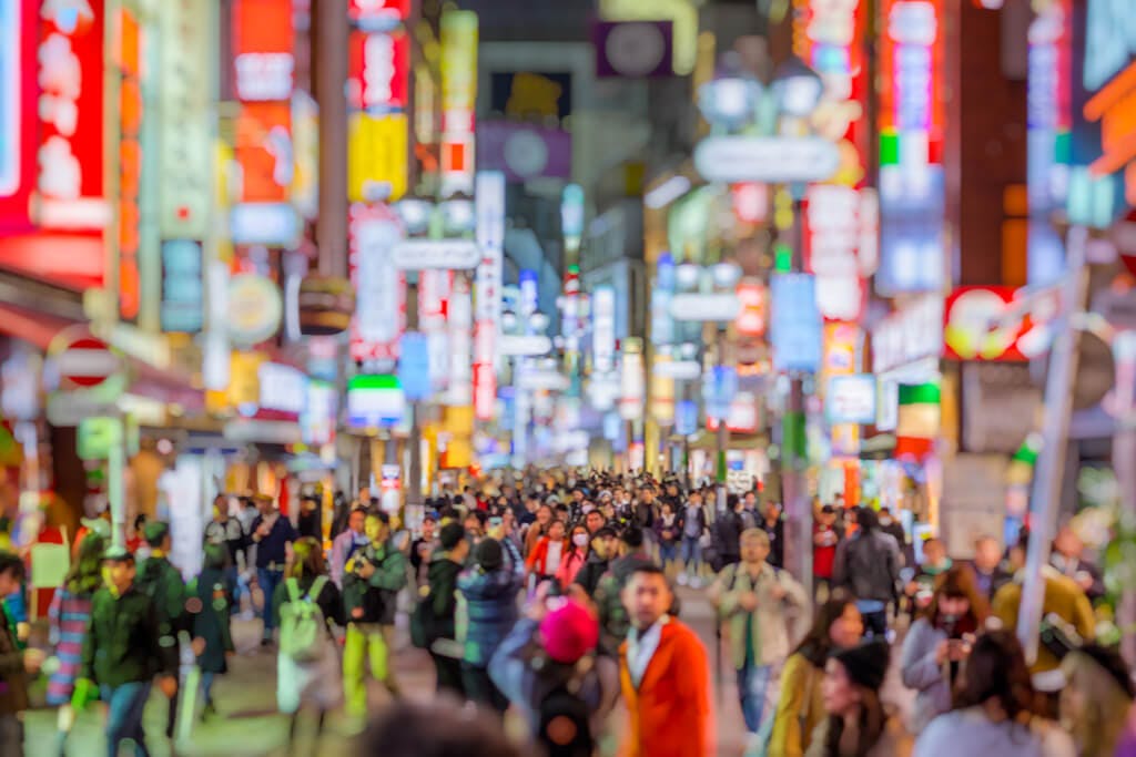 The streets of Shibuya at night with many people walking and many signs lit up
