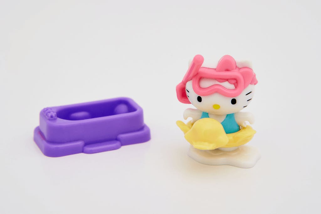 A cute little bath time Hello Kitty figure wearing a snorkeling set and inner tube with a miniature bathtub next to her.