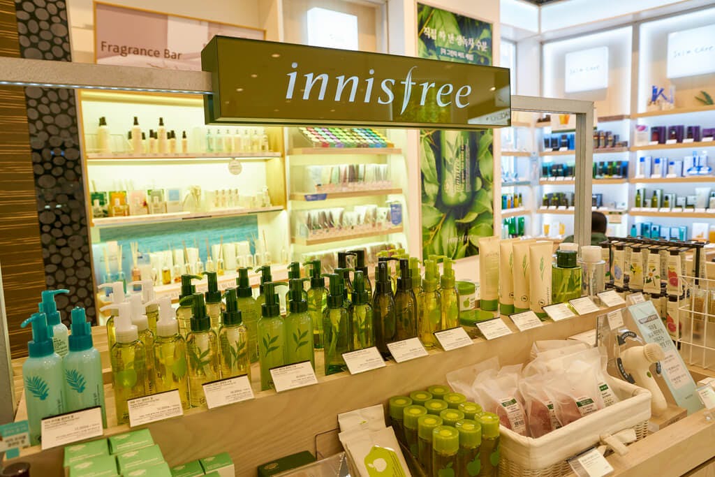 The inside of an innisfree section in a store with many green and white products.