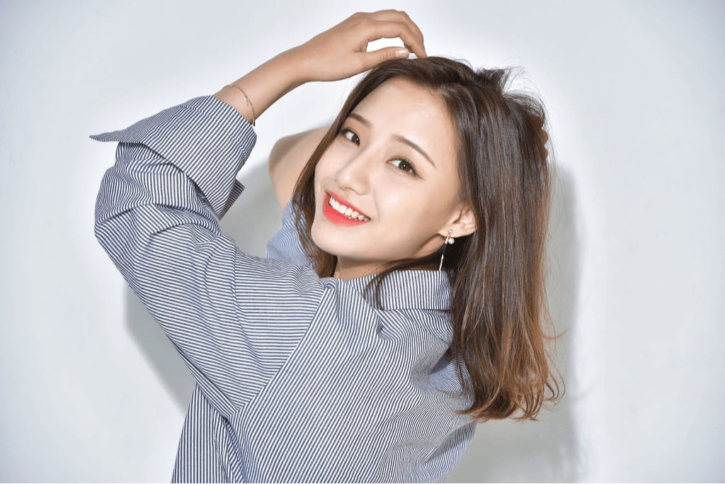 A woman turns and smiles at the camera showing off her hair, which is shiny and smooth thanks to Japanese hair care secrets.