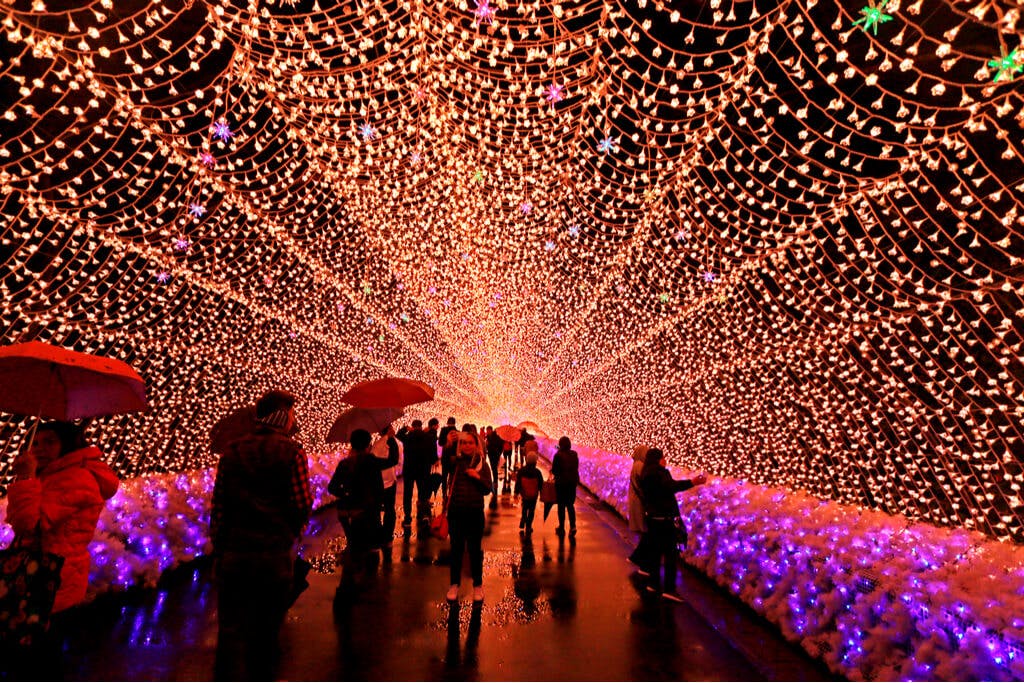 The light tunnel in Nagoya with many people walking underneath holding umbrellas or taking pictures.