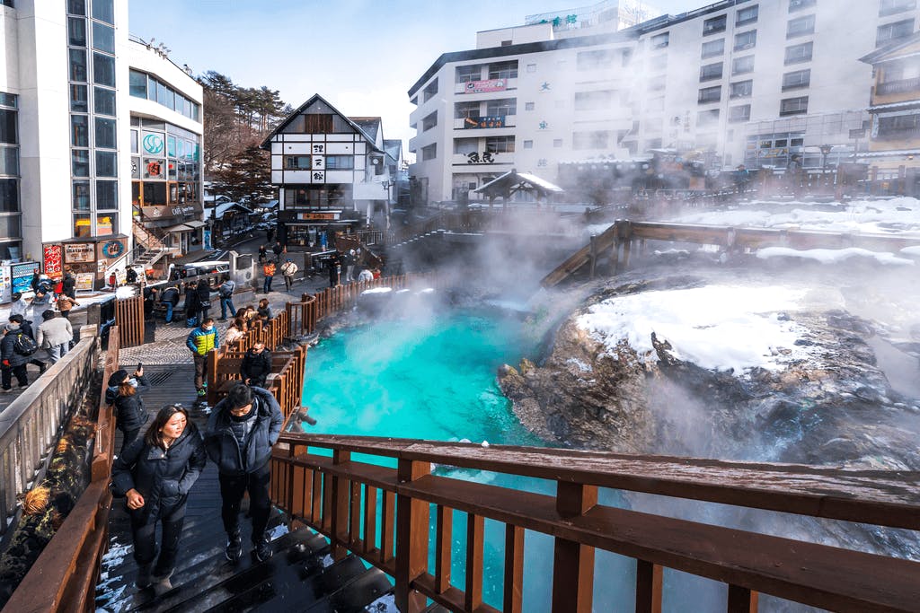 A group of tourists walk around a popular Japanese onsen in a popular hot spring town.